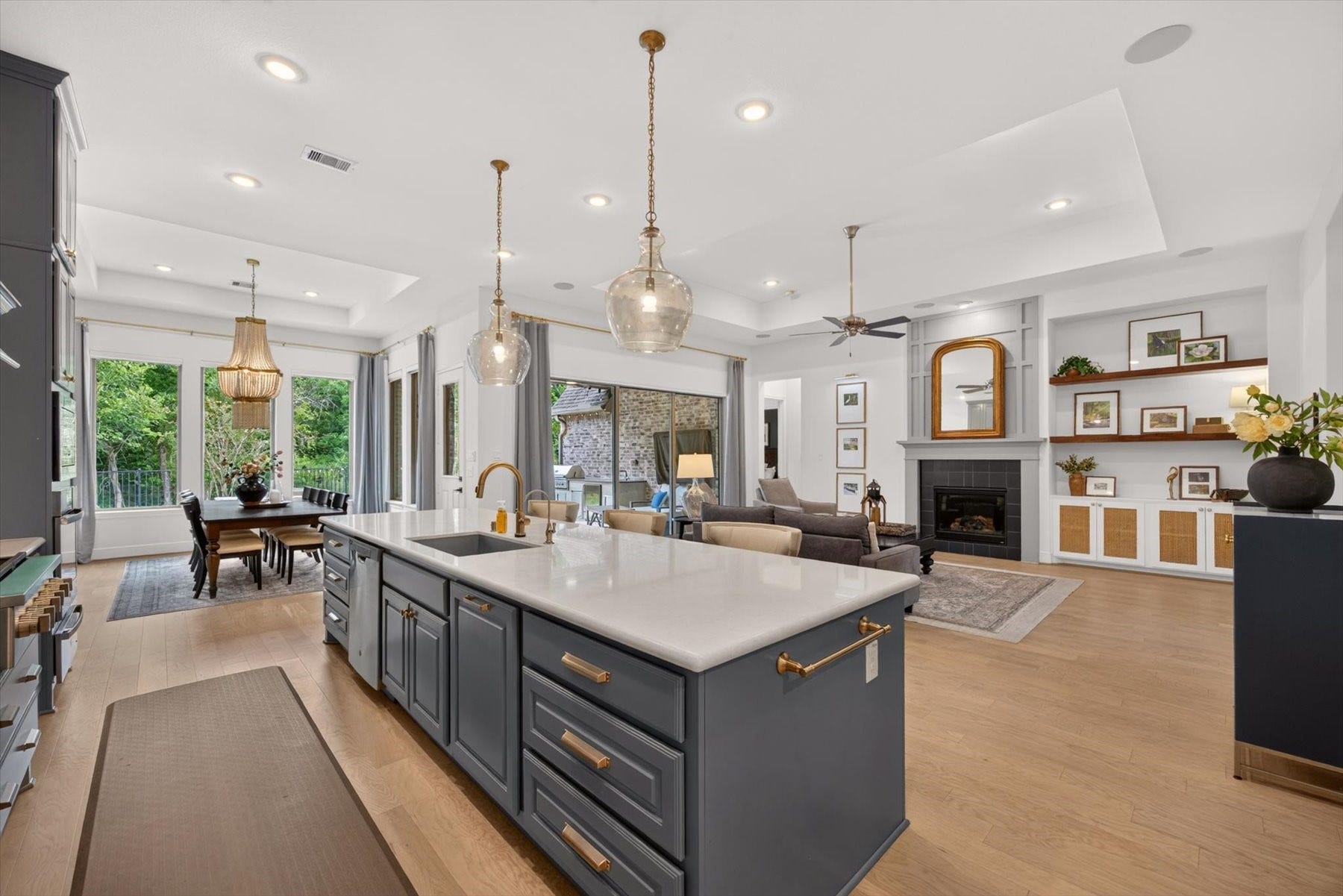 1219 Mcmurtry Ridge Drive, Katy, TX 77494 Spacious open-concept kitchen and living area featuring a large center island, custom cabinetry, elegant pendant lighting, and a cozy fireplace.