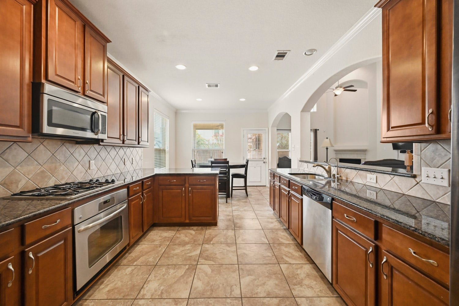 The spacious galley-style layout flows effortlessly into a sunny breakfast nook with outdoor access, while wide architectural arches open up direct sightlines into the living room.