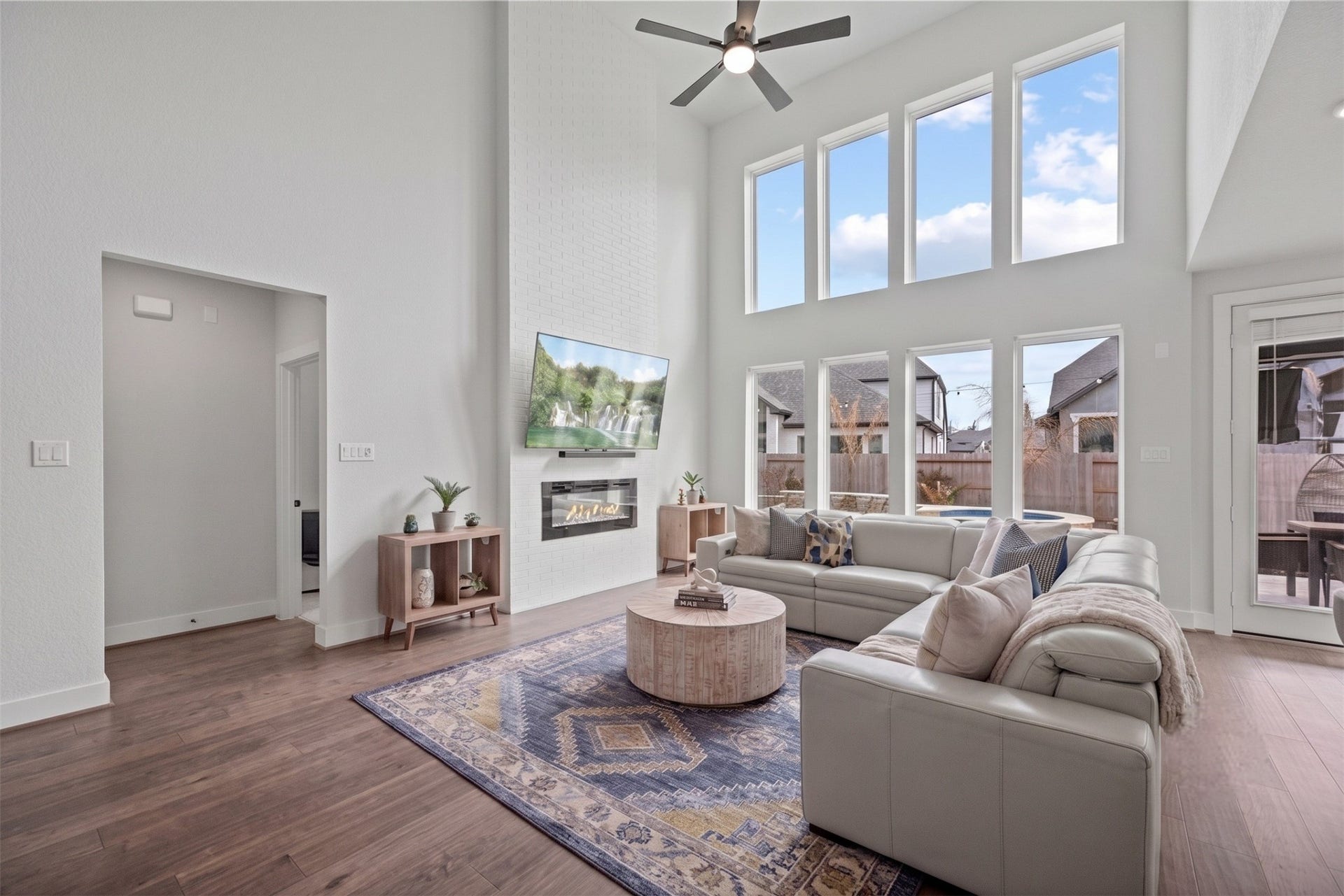 Sun-drenched living space with dramatic two-story ceiling, sleek engineered wood planks, cozy fireplace, tons of charm! Virtually staged.