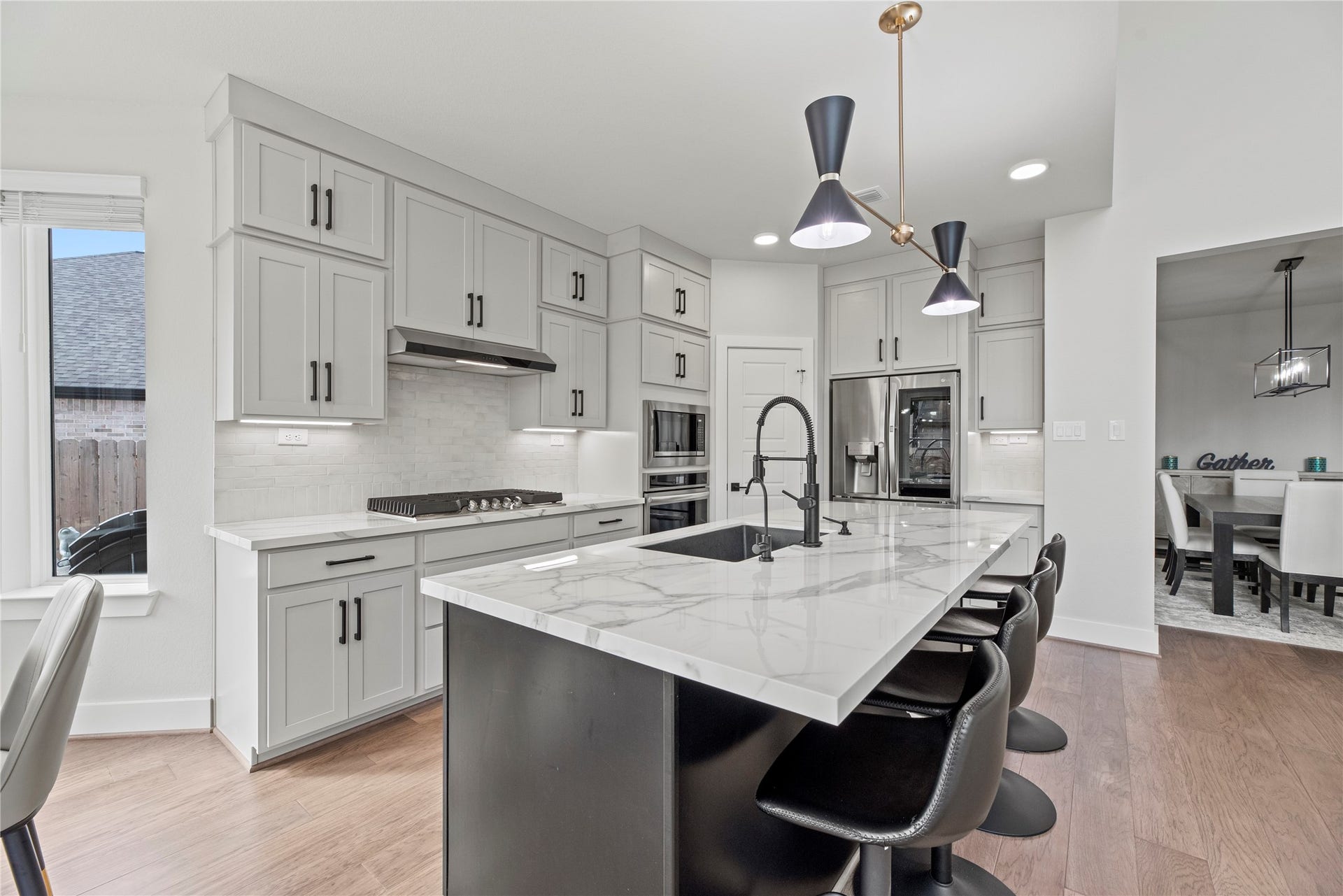 The kitchen features a coordinating backsplash and rich white cabinetry with under-cabinet lighting, adding a refined touch and elevating the overall feel of the space.