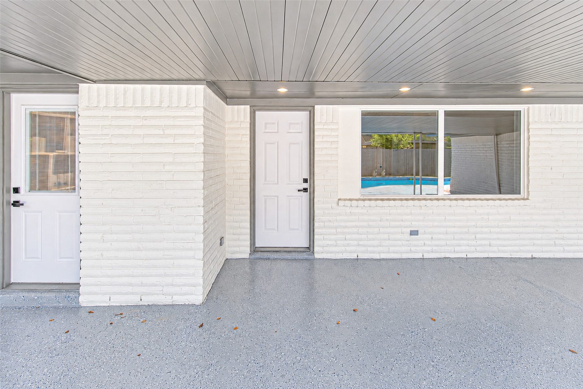 Charming covered patio area with modern white brickwork and a view of the inviting pool, perfect for outdoor relaxation and entertainment.