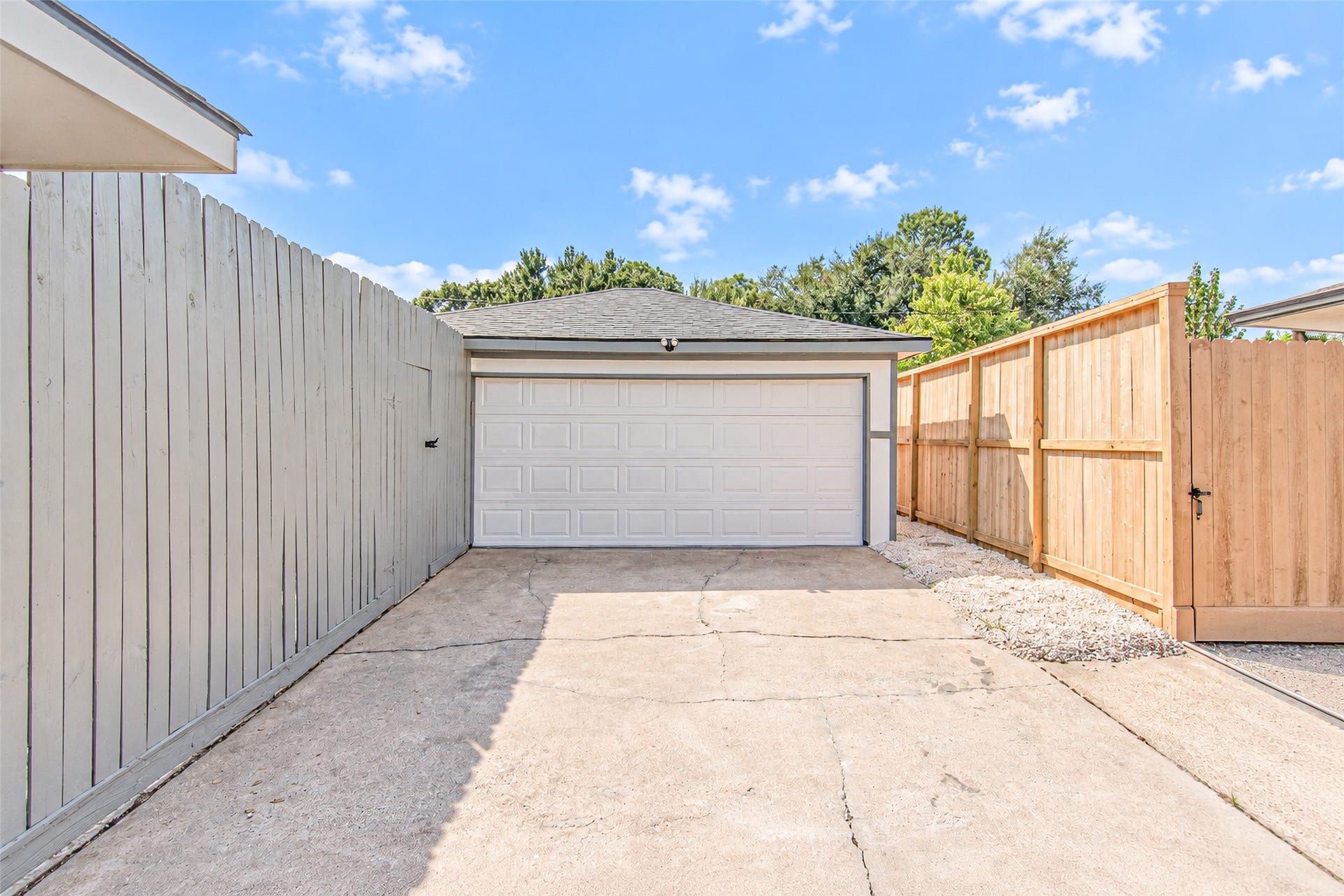 Expansive detached garage with a wide driveway, flanked by privacy fencing for ultimate seclusion and convenience.