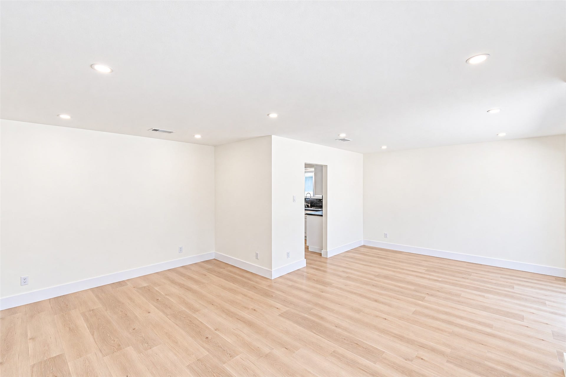 A spacious dining room bathed in natural light, featuring elegant wood flooring and seamless flow into the kitchenperfect for entertaining and creating cherished memories.