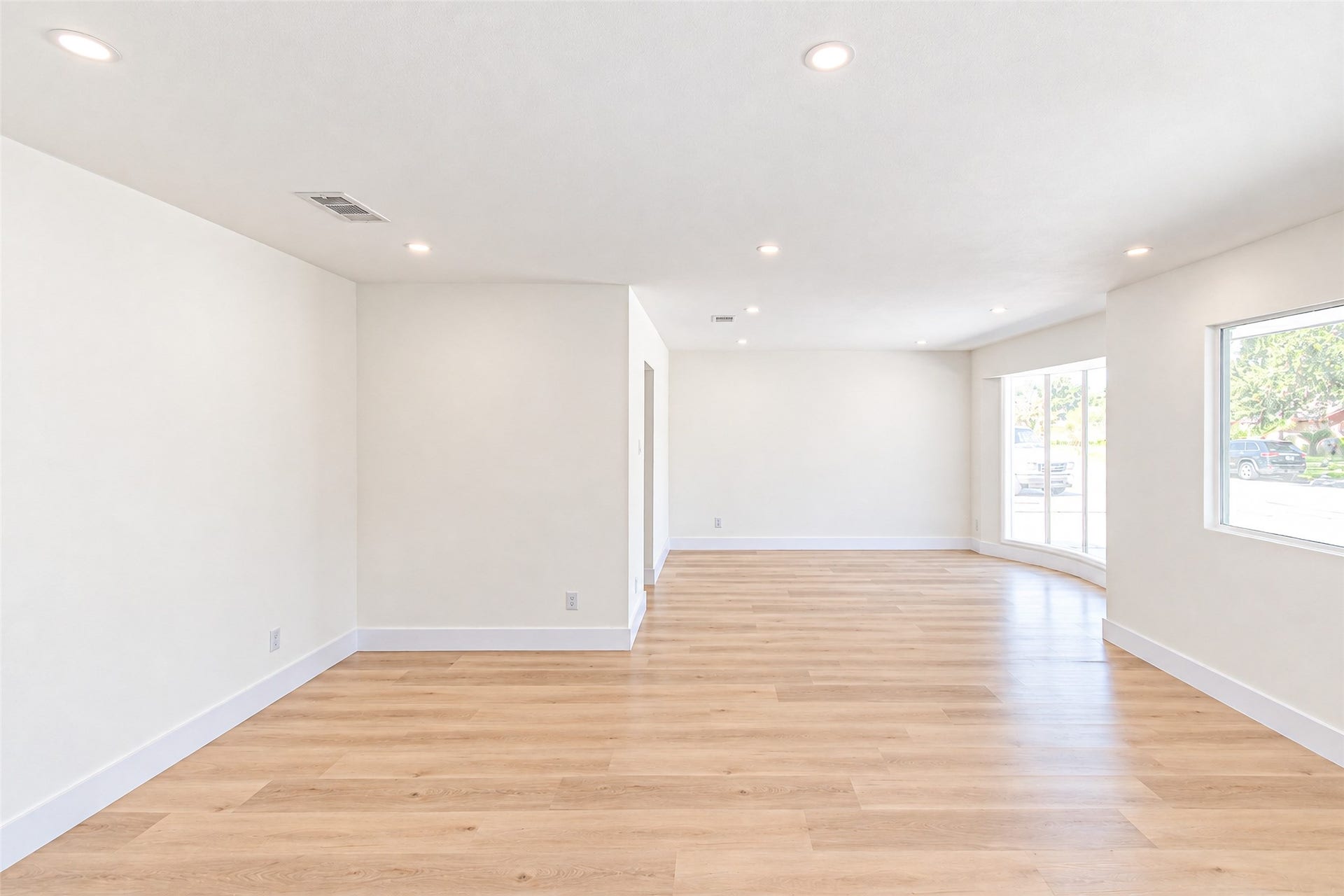 Experience the perfect setting for entertaining in a bright and airy dining room, featuring expansive windows and elegant wood flooring.