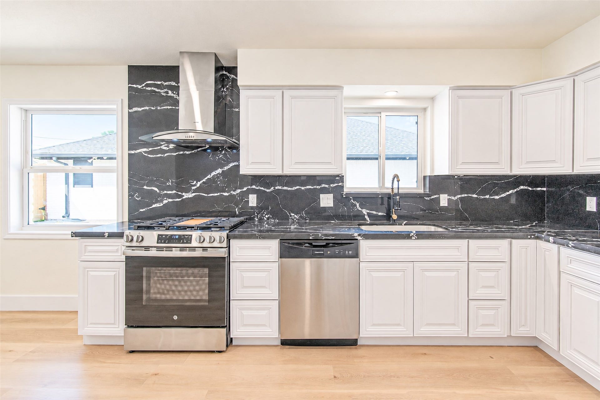 Culinary bliss awaits in this modern kitchen, where sleek stainless steel appliances harmonize with elegant black marble countertops and crisp white cabinetry.