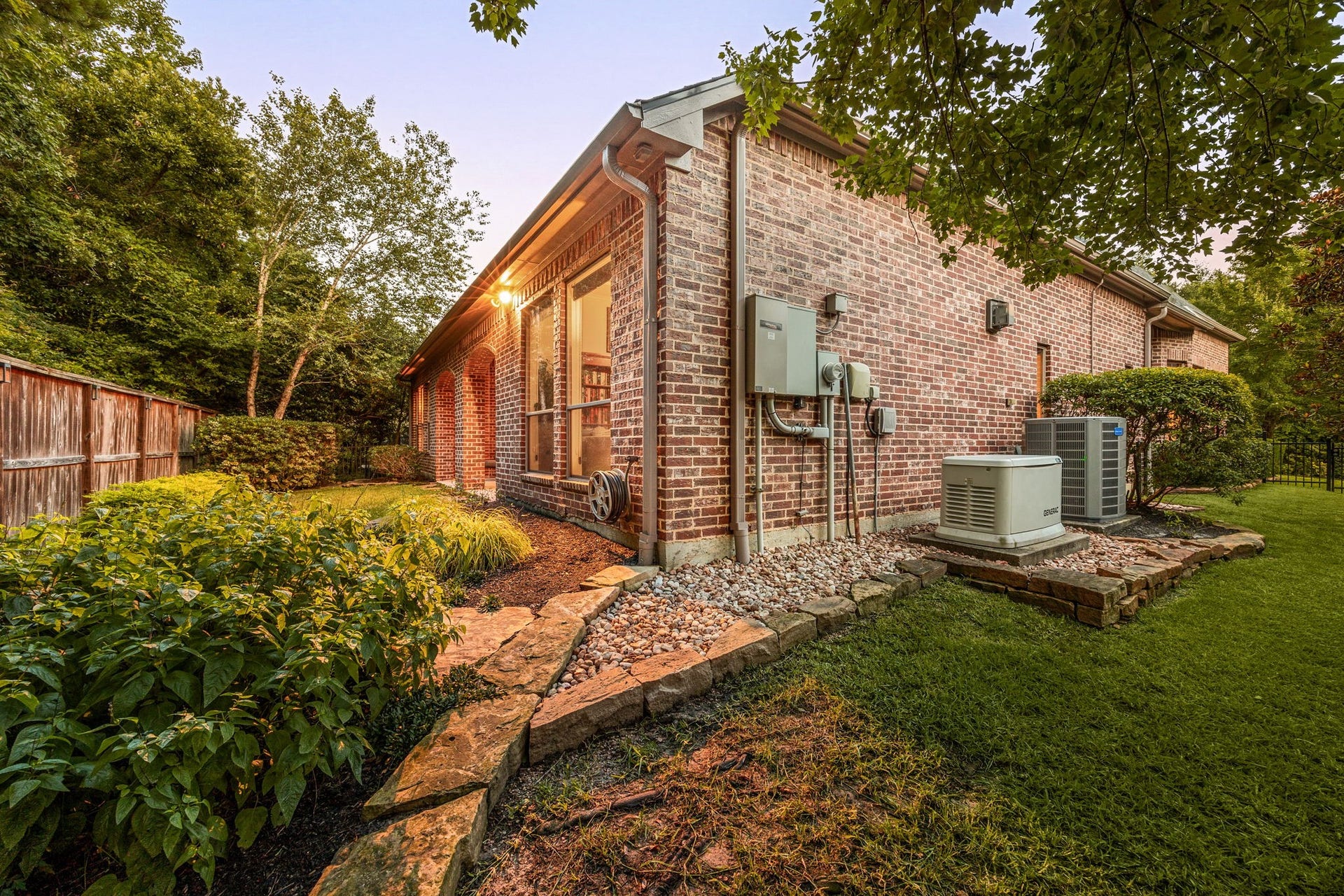 195 Oarwood Place, The Woodlands, TX 77389 This immaculate side yard features a winding natural stone walkway through manicured garden beds, bordered by a sturdy wood privacy fence and mature trees. The zone is equipped with a premium Generac automatic home standby generator and dual high-efficiency HVAC units, ensuring uninterrupted power and optimal comfort for the entire estate year-round.