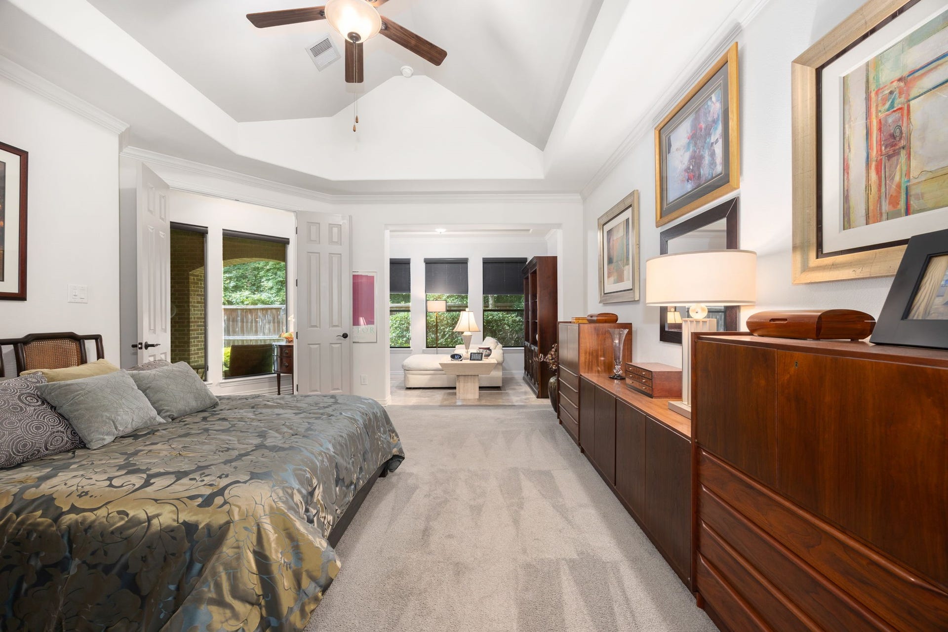 195 Oarwood Place, The Woodlands, TX 77389 Spacious primary suite featuring a tray ceiling, ceiling fan, and a private sitting areaperfect for reading, relaxing, or enjoying your morning coffee. Large windows fill the space with natural light, creating a bright and peaceful retreat.