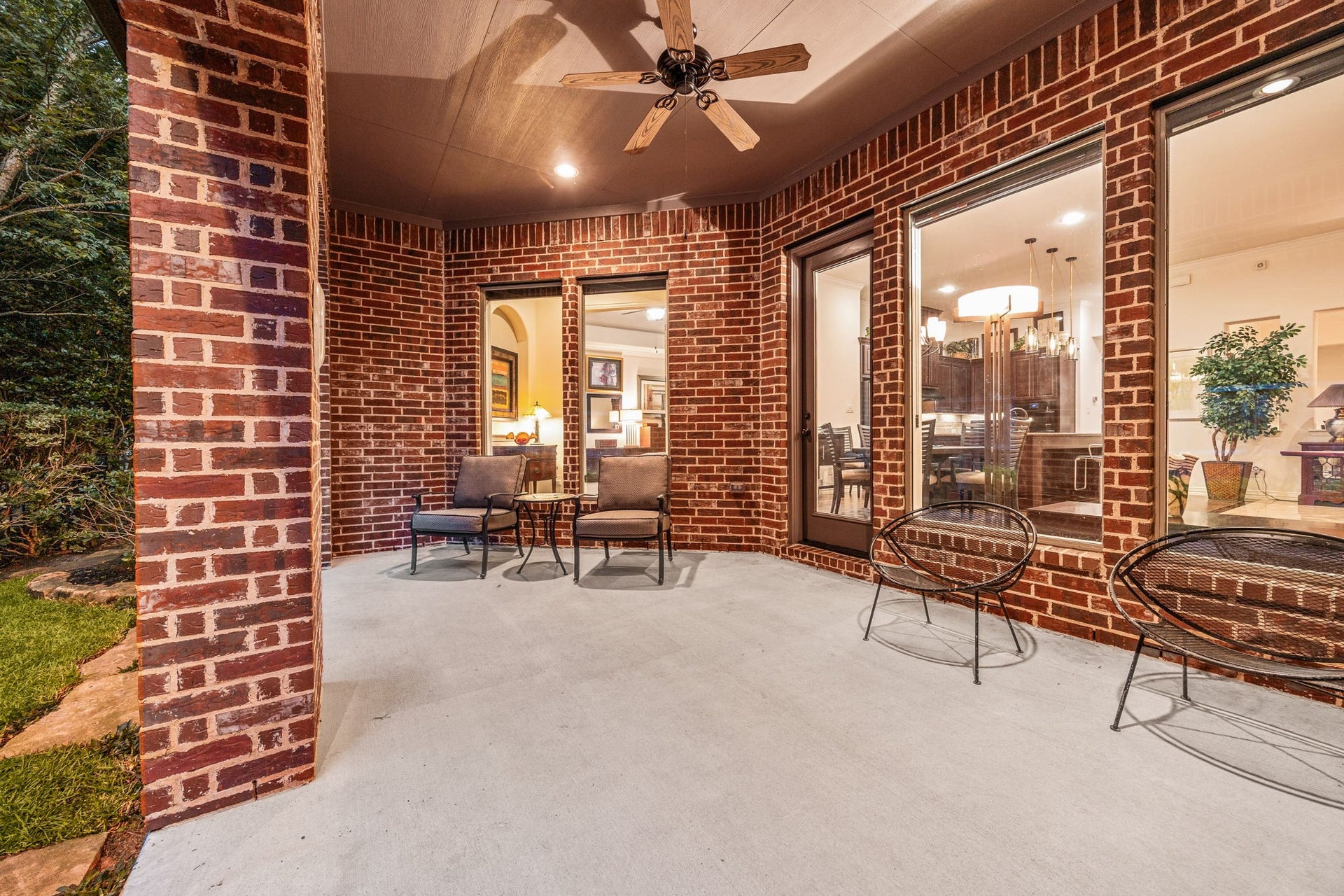 195 Oarwood Place, The Woodlands, TX 77389 This sweeping covered back patio is designed for premium year-round outdoor entertaining. Built with timeless, full-brick structural columns, the spacious concrete pavilion features an integrated ceiling fan to maximize natural breezes and recessed spotlights for cozy evening lighting. Oversized windows and a grand glass door provide clear, continuous visual flow to the home's open interior layout.