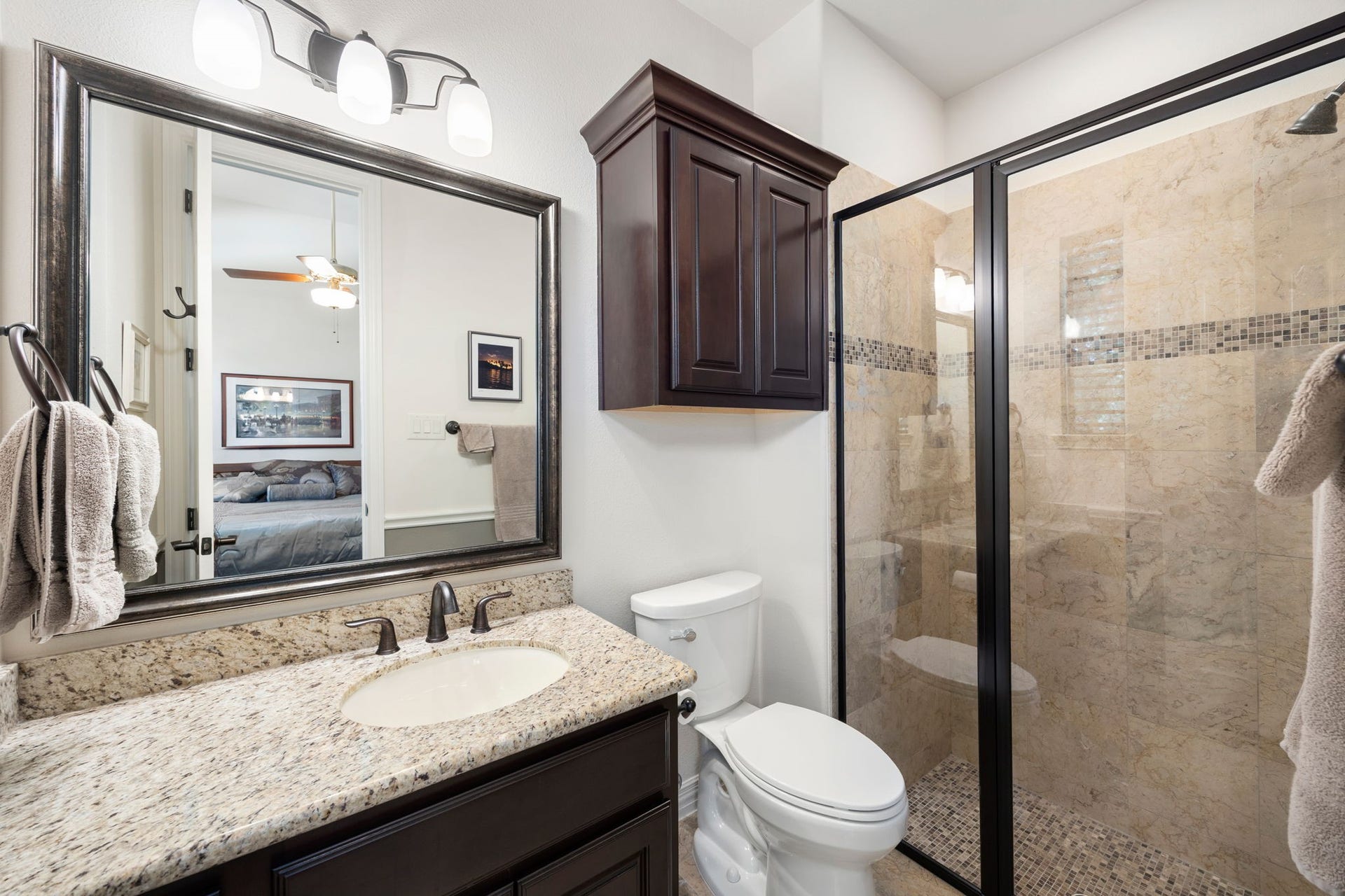 195 Oarwood Place, The Woodlands, TX 77389 This private en-suite bathroom offers granite countertops, custom cabinets, and a beautifully tiled shower, providing comfort and convenience for family or guests.