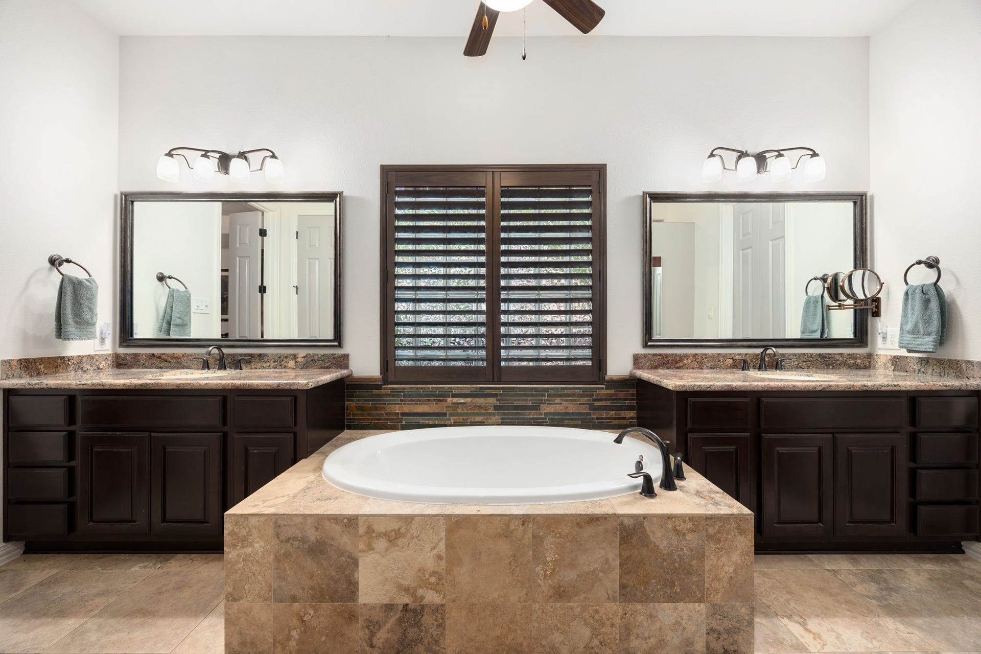 195 Oarwood Place, The Woodlands, TX 77389 The spacious primary bathroom offers a spa-like feel with dual vanities, a relaxing soaking tub, and a separate walk-in shower. Rich wood cabinetry provides abundant storage, while elegant finishes and thoughtful design create a bright and inviting retreat.