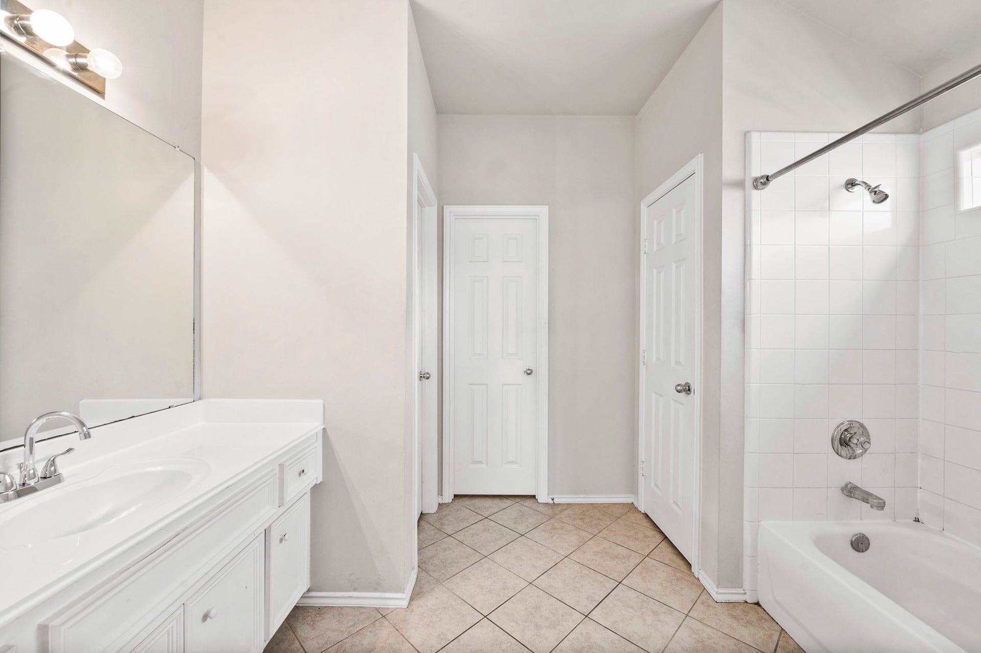 6322 Sunlit Orchard Drive, Houston, TX 77072 Bright and spacious bathroom featuring a sleek white vanity with ample storage, a large mirror, and a tiled shower-tub combo for a modern touch.