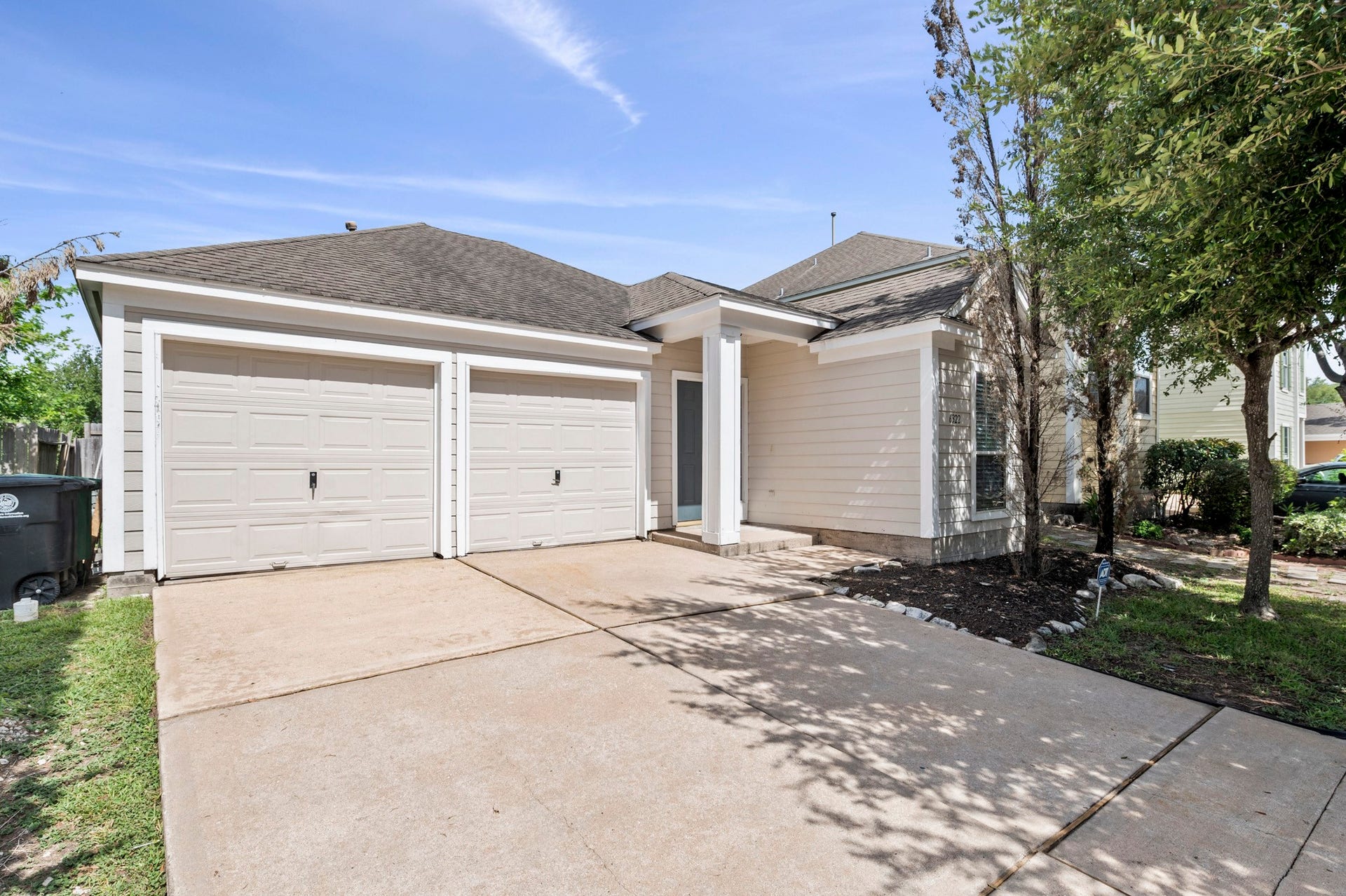 6322 Sunlit Orchard Drive, Houston, TX 77072 Spacious two-car garage with a wide driveway and charming entryway, surrounded by mature trees and well-maintained landscaping.