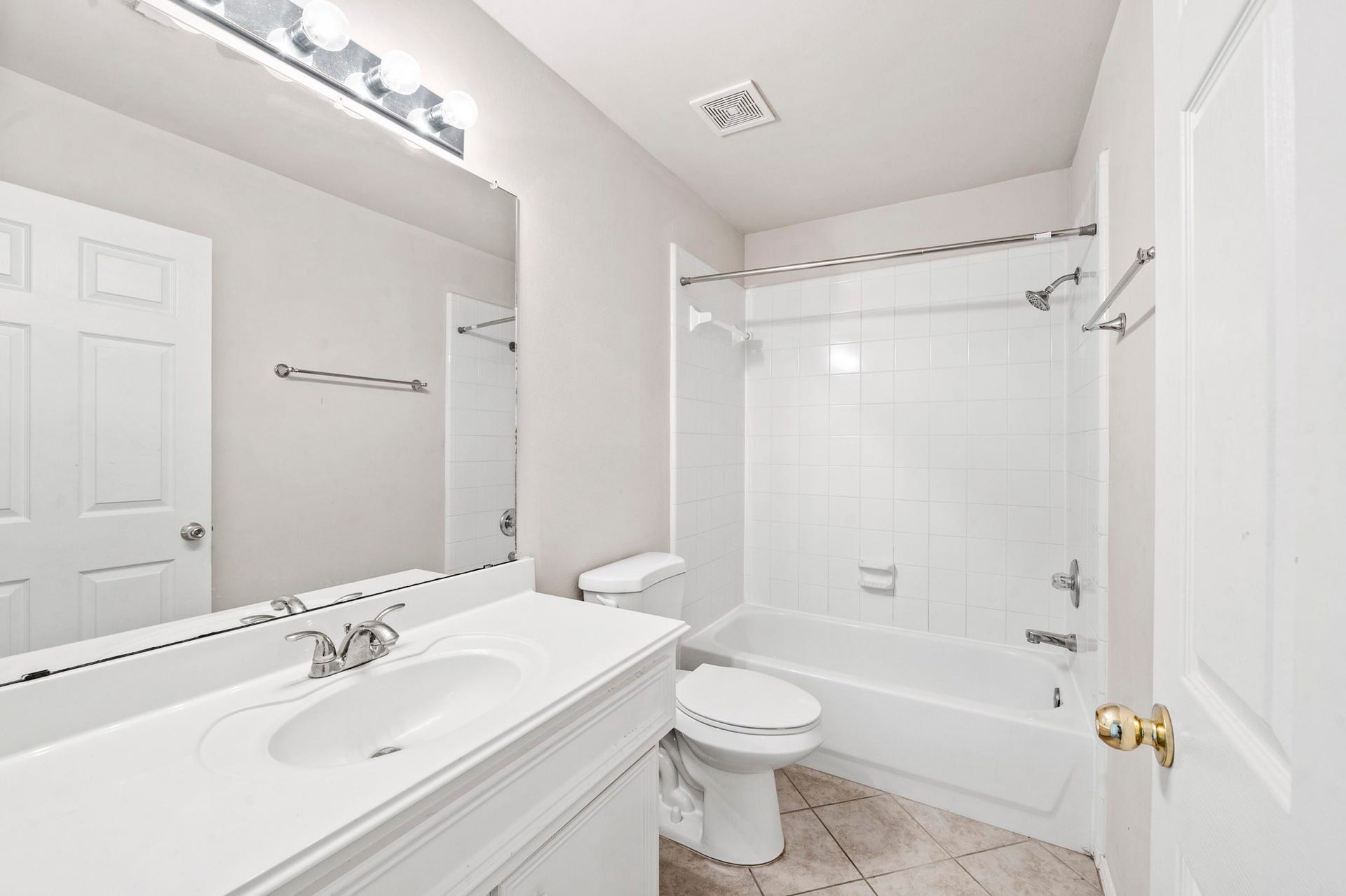 6322 Sunlit Orchard Drive, Houston, TX 77072 Bright, clean bathroom featuring a large vanity mirror, classic white fixtures, and a tiled shower-tub combination.
