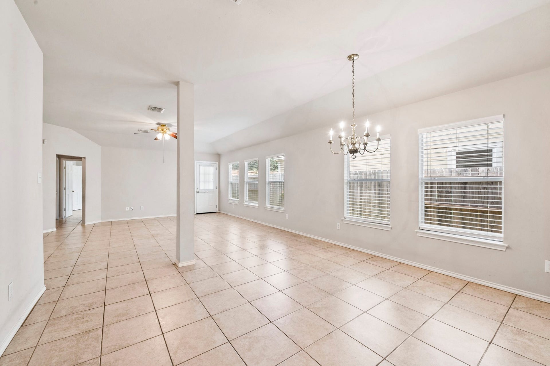 6322 Sunlit Orchard Drive, Houston, TX 77072 Spacious open-plan living area with abundant natural light, featuring elegant tile flooring and a charming chandelier, perfect for versatile living and dining arrangements.