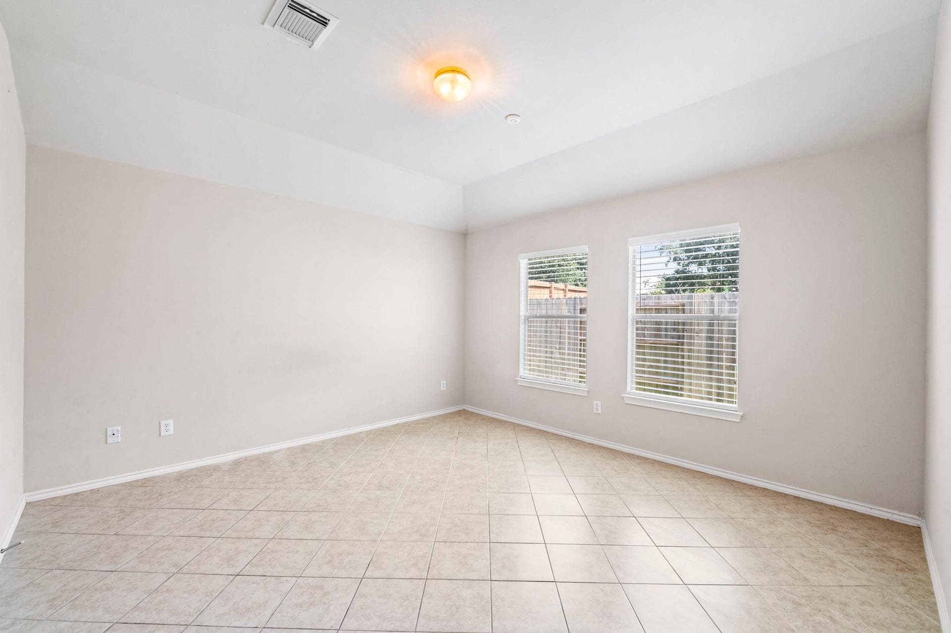 6322 Sunlit Orchard Drive, Houston, TX 77072 Bright, airy room featuring tiled floors, neutral walls, and large windows offering plenty of natural light and a view of the backyard.