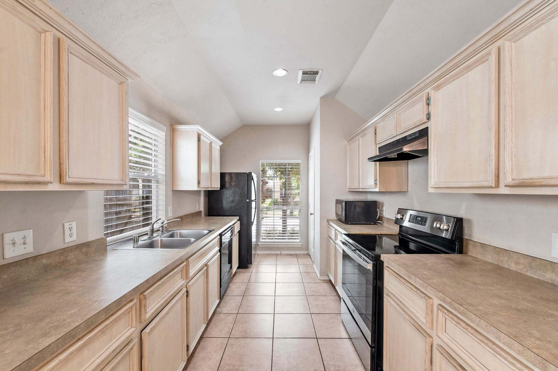 6322 Sunlit Orchard Drive, Houston, TX 77072 Charming galley kitchen with ample cabinetry, modern appliances, and a window bringing in natural light, perfect for cozy meal preparations.