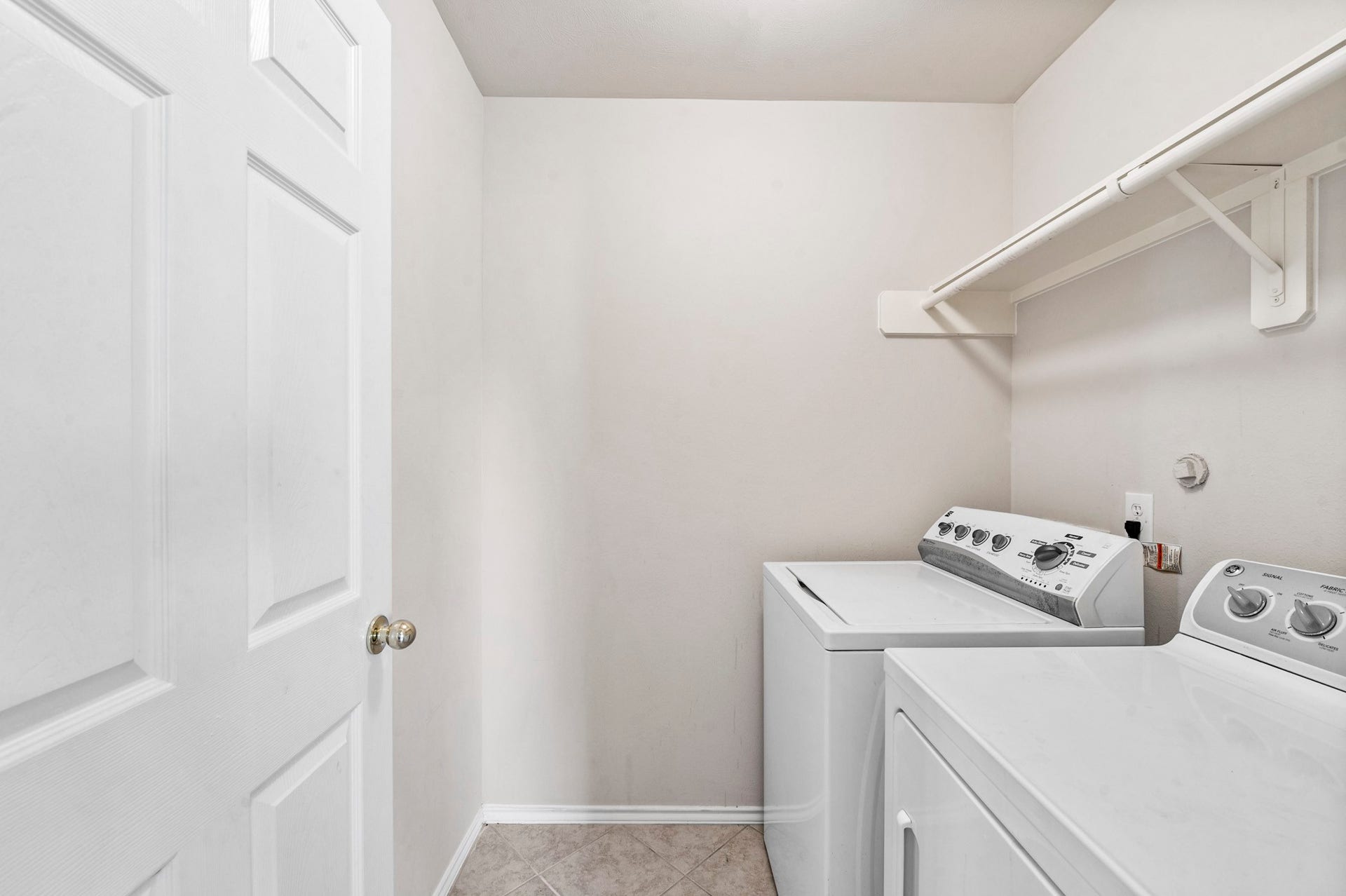 6322 Sunlit Orchard Drive, Houston, TX 77072 Convenient laundry room with washer, dryer, and overhead shelving for easy organization.