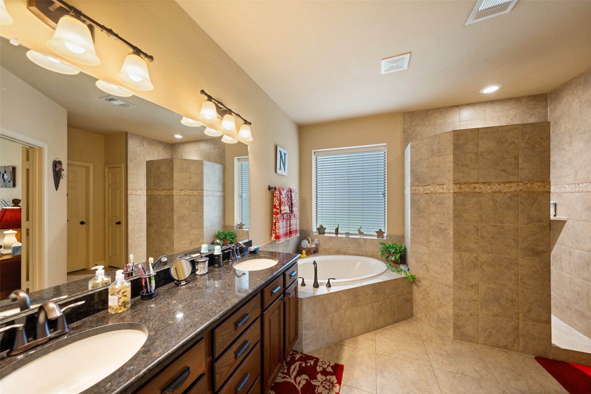 903 Weeping Willow Way, Magnolia, TX 77354 Primary bathroom featuring a spacious corner bathtub, elegant granite countertops with dual sinks, and a beautifully tiled walk-in shower.
