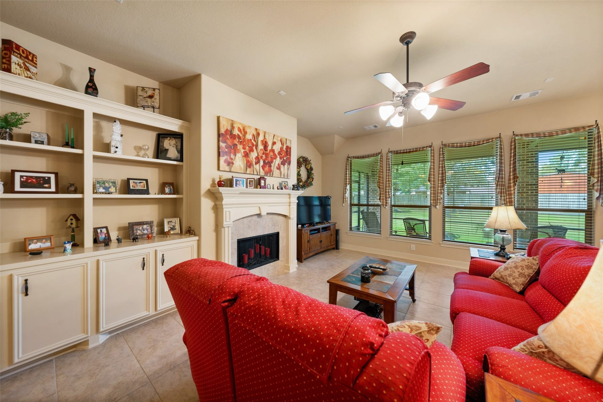 903 Weeping Willow Way, Magnolia, TX 77354 Living room featuring a gas fireplace, custom built-in shelves, and large windows that overlook back yard and extended outdoor living area.