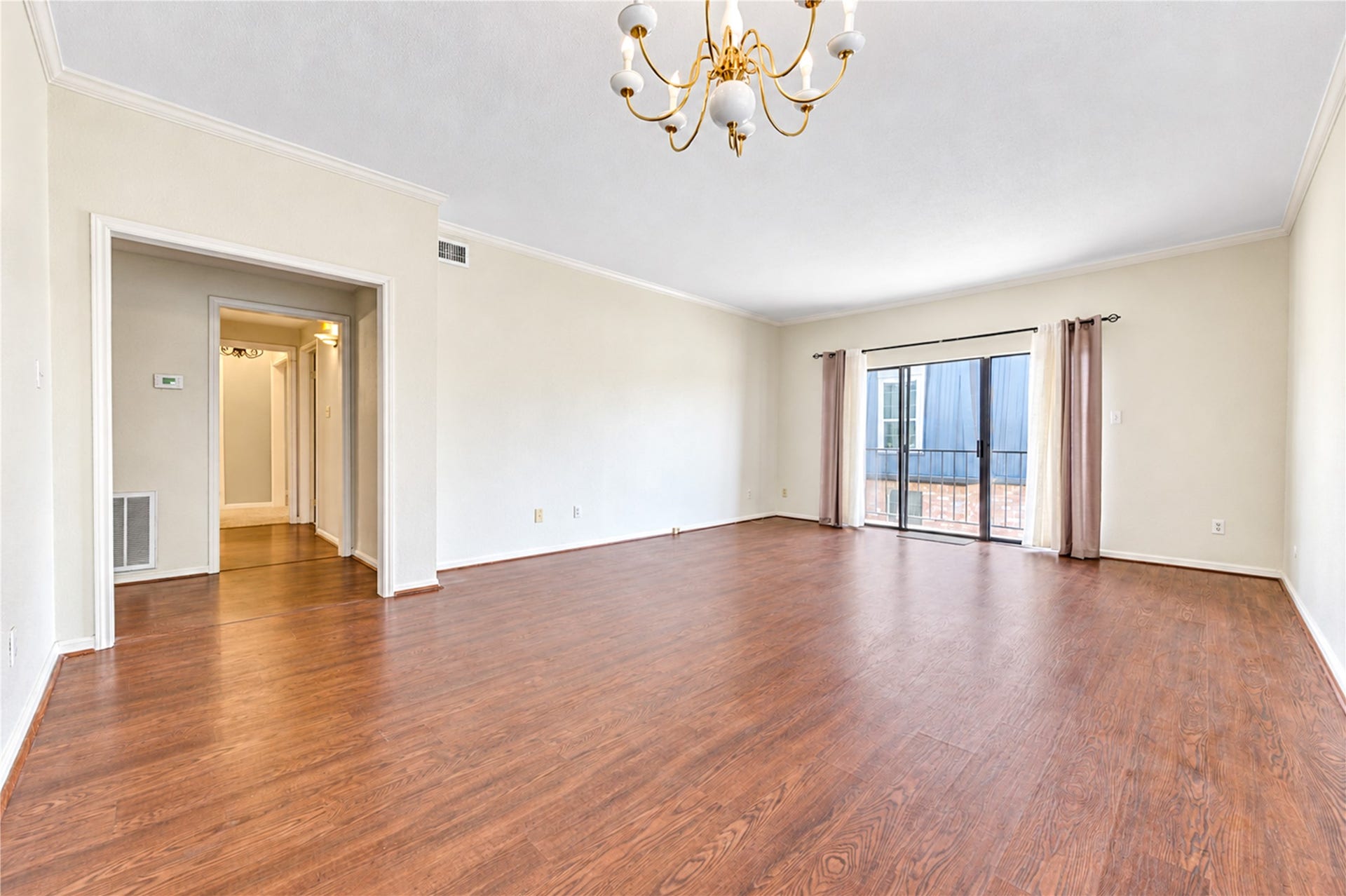 Spacious living area with elegant wood flooring and large sliding glass doors, offering abundant natural light.
