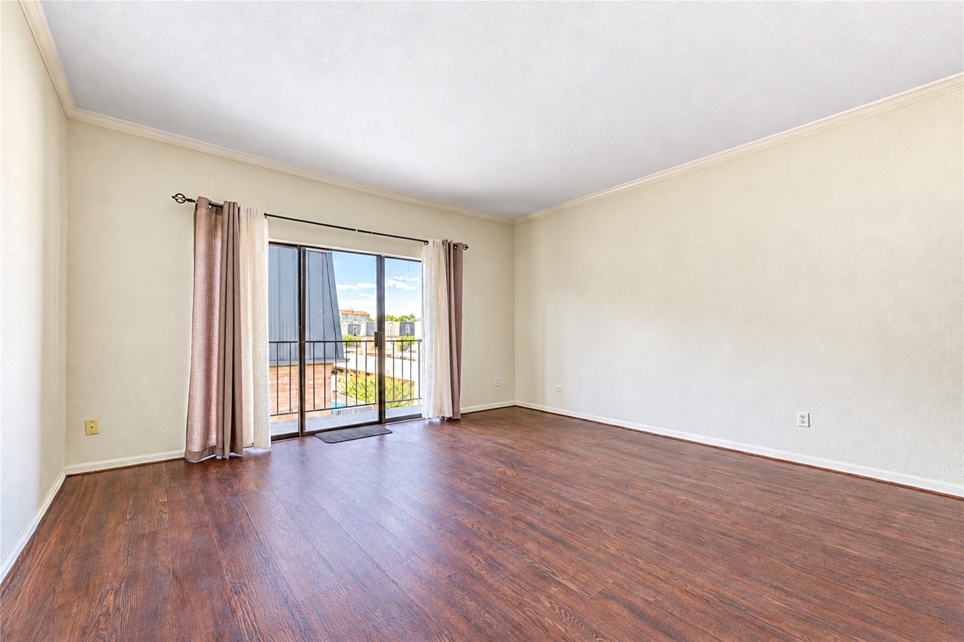 Spacious living area with elegant wood flooring and a classic chandelier, leading to a cozy kitchen with white cabinetry and appliances.
