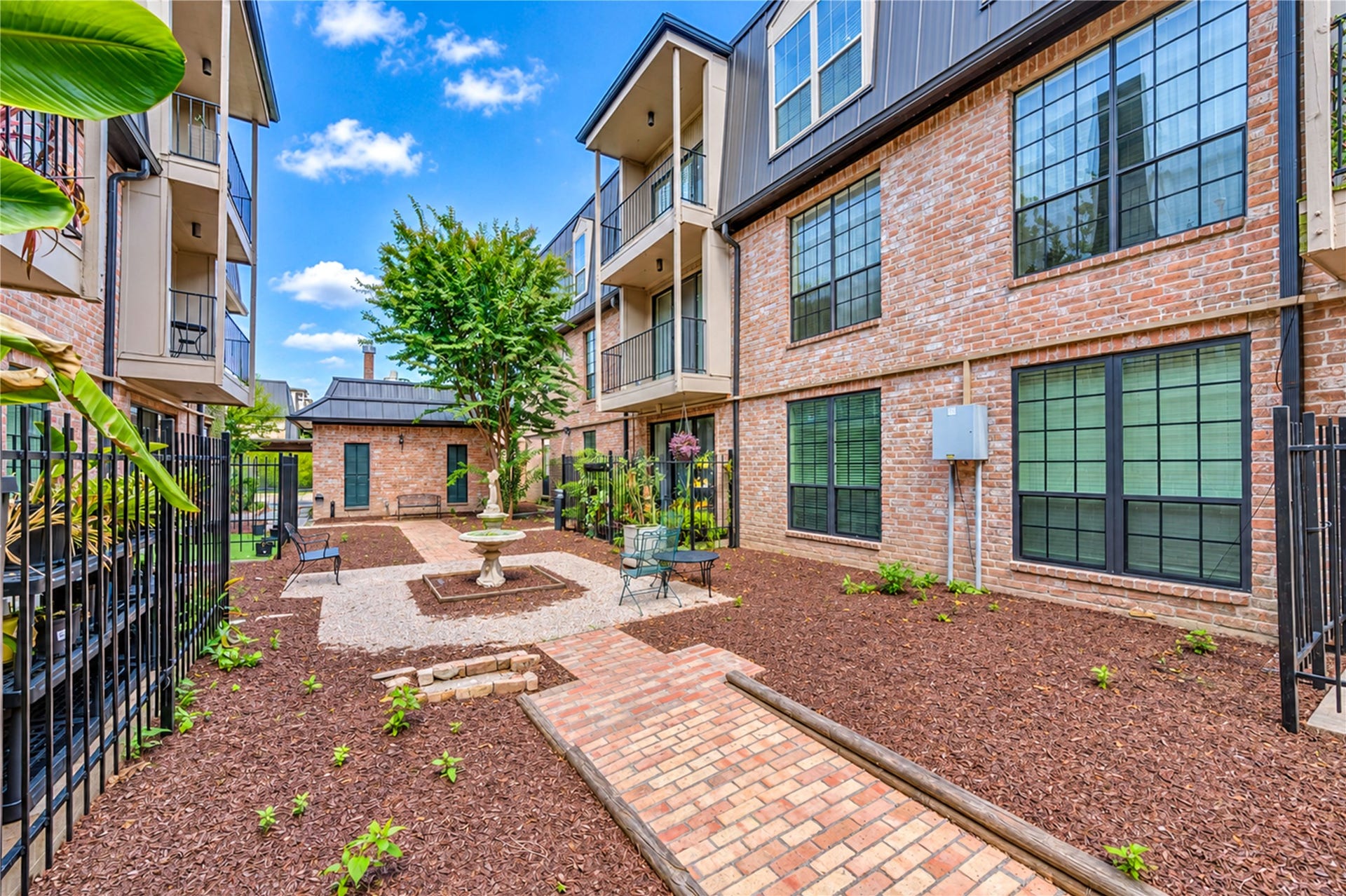 Charming gated community entrance surrounded by lush greenery and mature trees offers privacy and security.