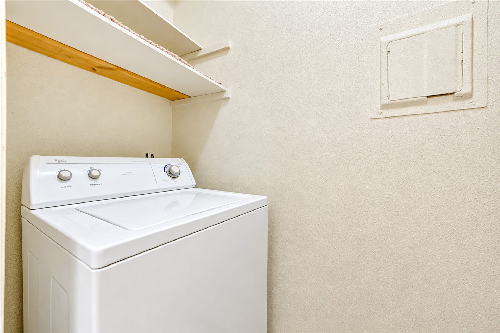 Cverhead shelving for storage.ompact laundry area with a top-loading washing machine and convenient o