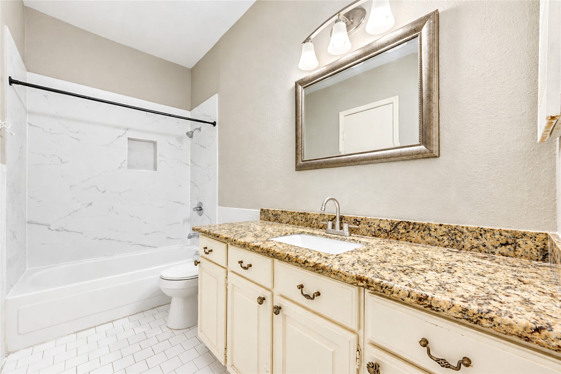 Charming galley kitchen with ample cabinetry, modern appliances, and warm wood flooring, leading to a convenient laundry area.