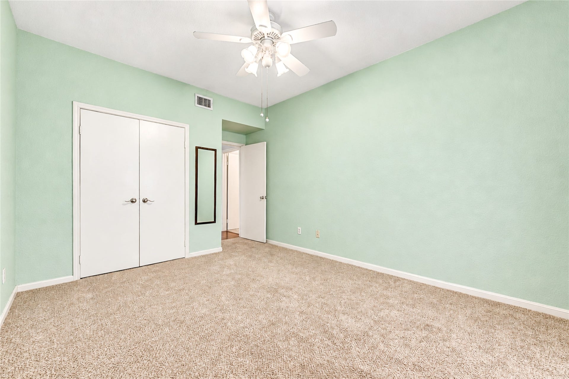 Spacious bedroom featuring soft carpet, neutral walls, a ceiling fan, and a large window for natural light.