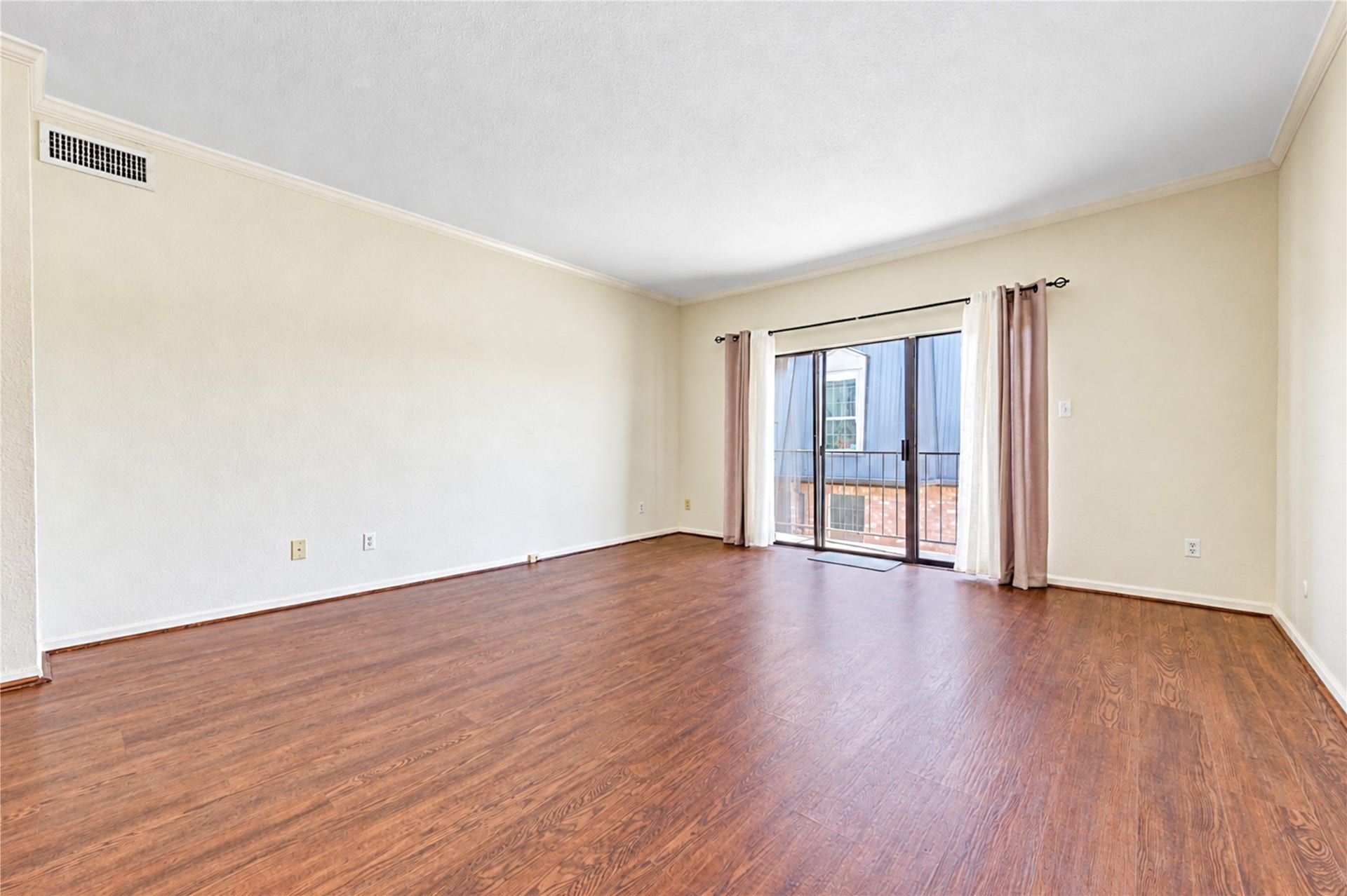 Elegant dining room with rich hardwood floors, a stylish chandelier, and ample natural light from a large window.
