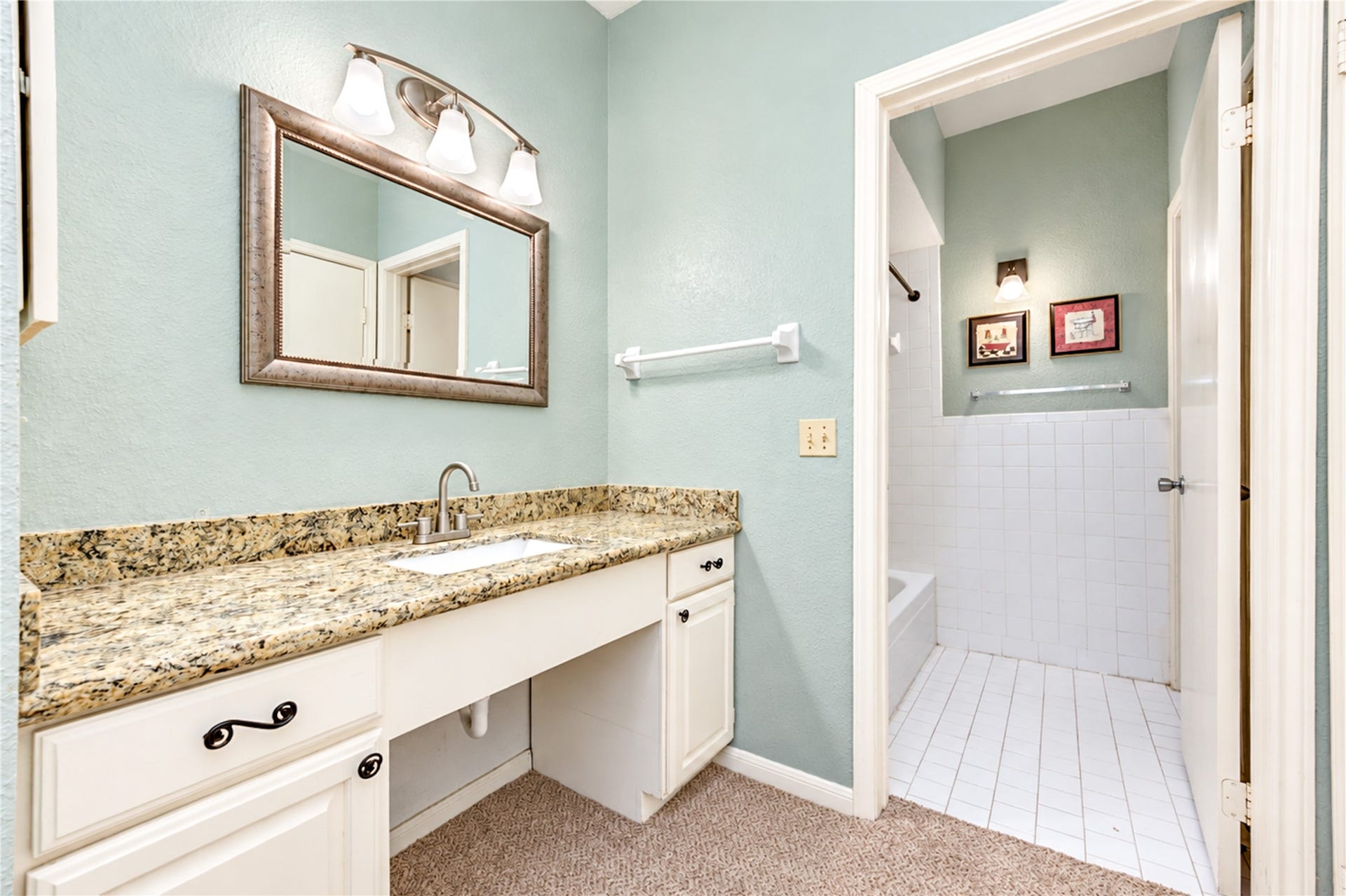 Charming bathroom vanity featuring a granite countertop, under-mount sink, and elegant lighting, complemented by soft pastel walls.