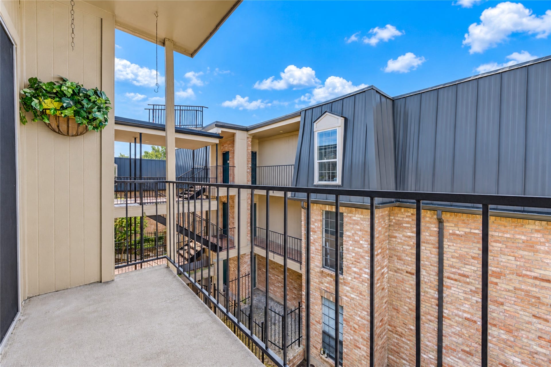 Charming balcony with sliding glass doors offers a peaceful outdoor retreat and scenic neighborhood views.