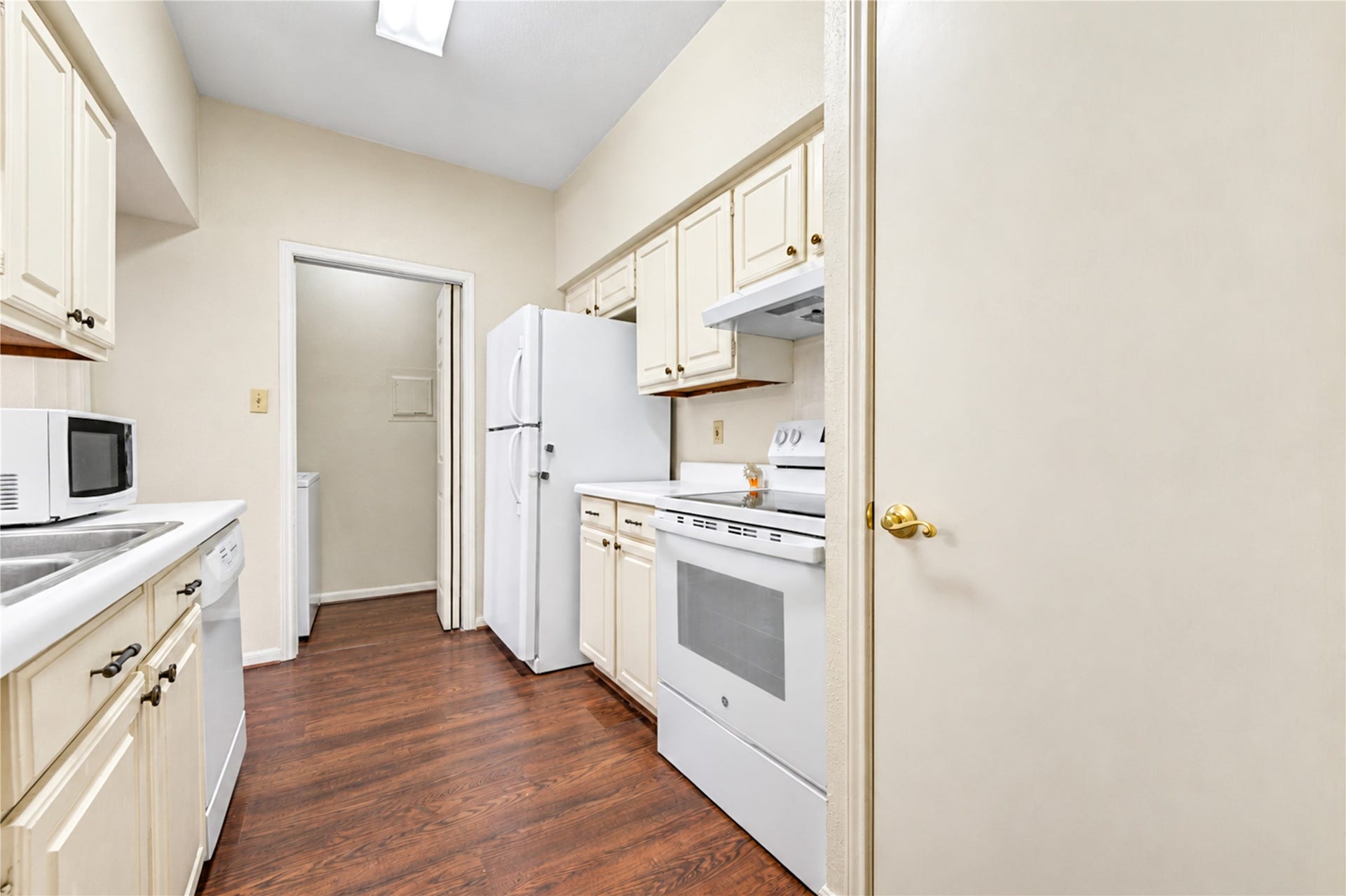 Bright kitchen with ample storage, featuring white cabinetry, a double sink, and modern appliances, perfect for culinary enthusiasts.