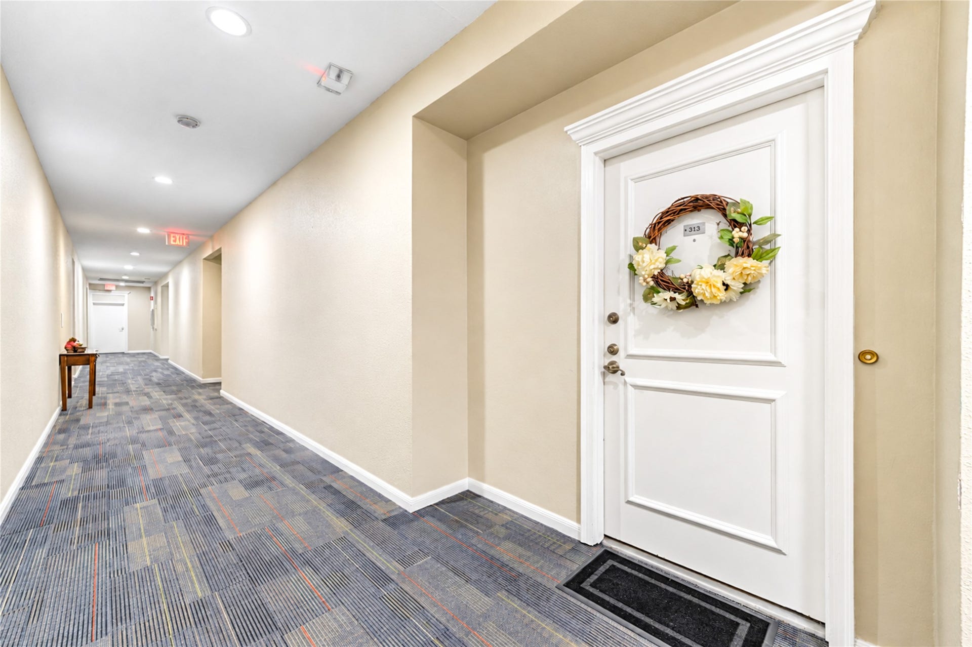 Inviting hallway entrance with a welcoming wreath on the door, featuring modern carpeting and soft lighting for a cozy ambiance.