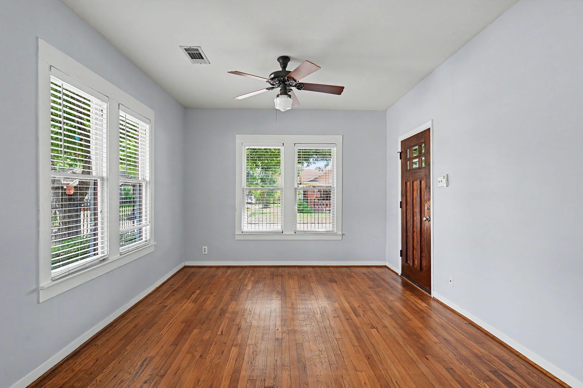 Large windows fill the living room with natural light, highlighting the beautiful hardwood floors.