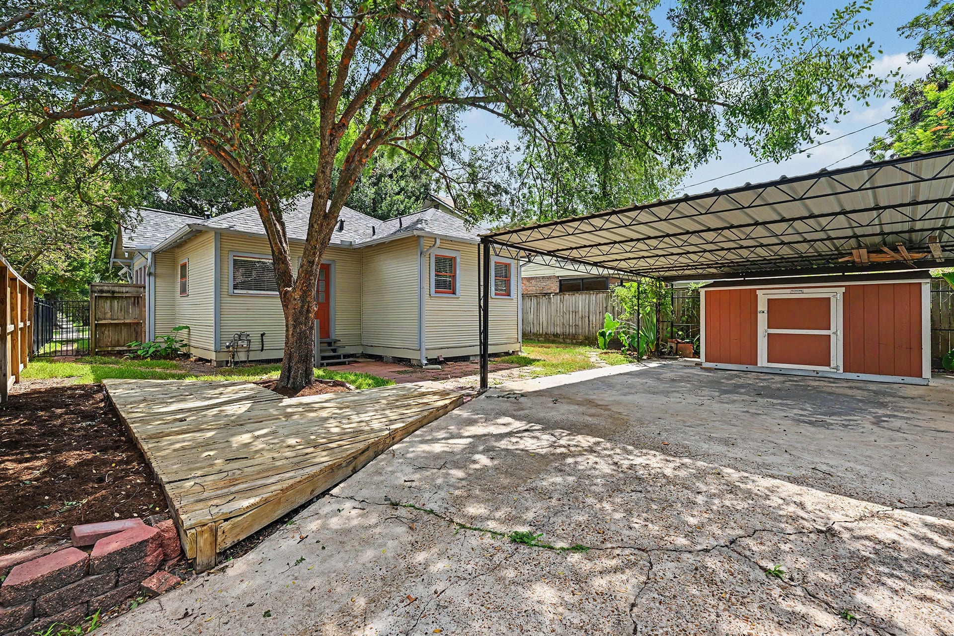 Fenced and private backyard offers space for outdoor living with a shaded deck area and patio. 2-car carport with storage shed.