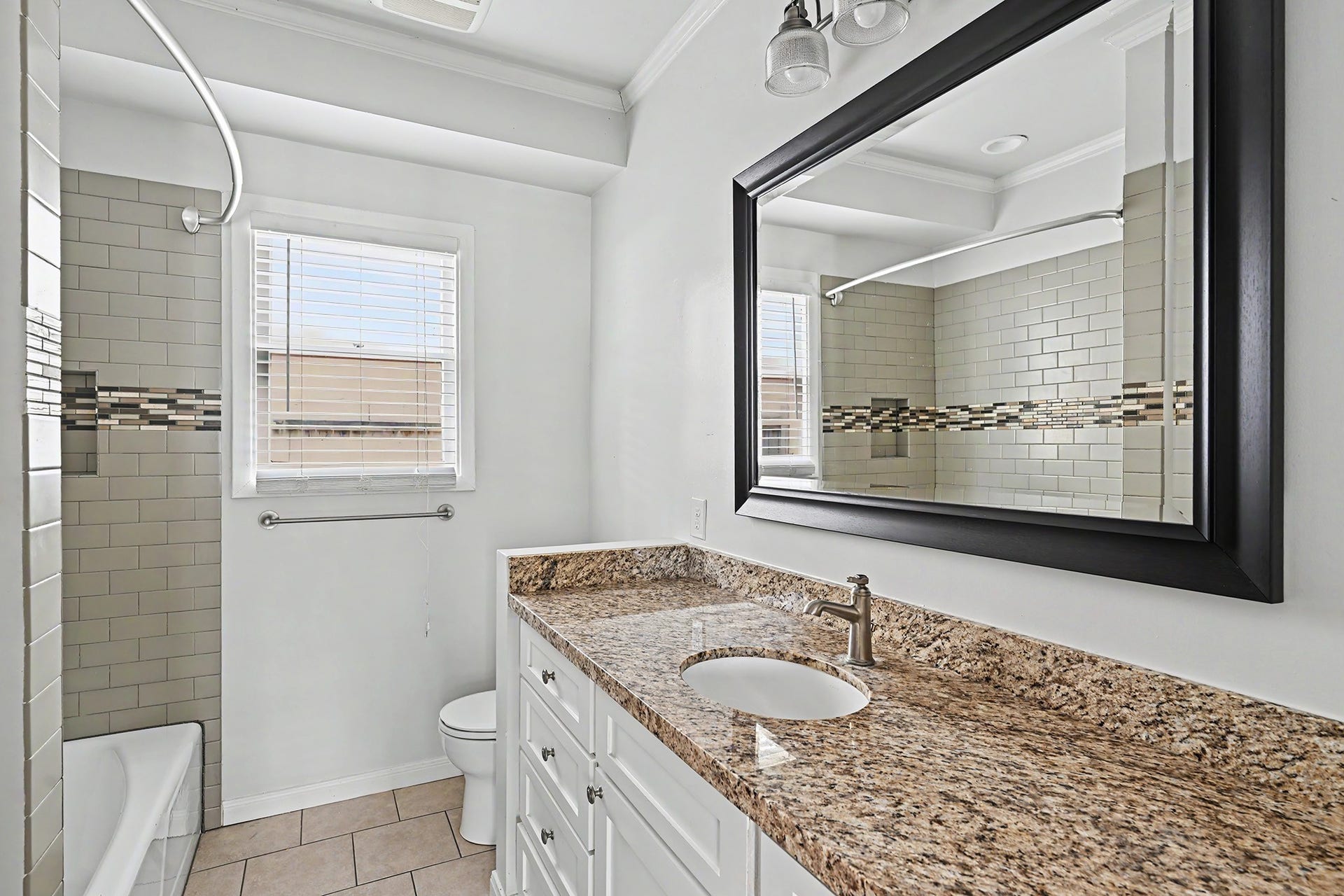 Updated hall bath features a tub/shower combination, large granite-topped vanity with great drawer storage, and timeless neutral finishes.