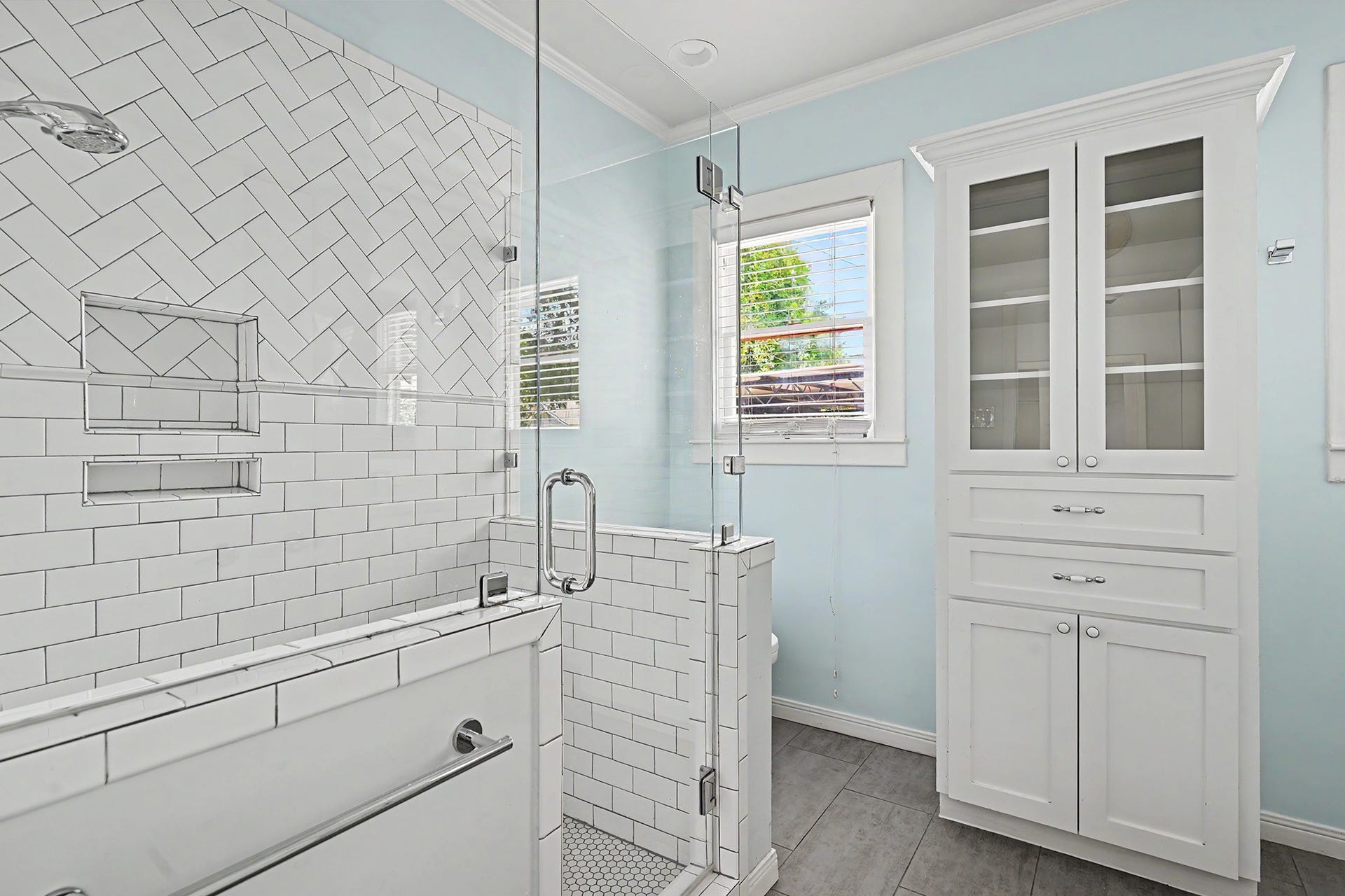 Updated, spa-like primary bath features a spacious walk-in shower with glass enclosure and timeless subway tile.