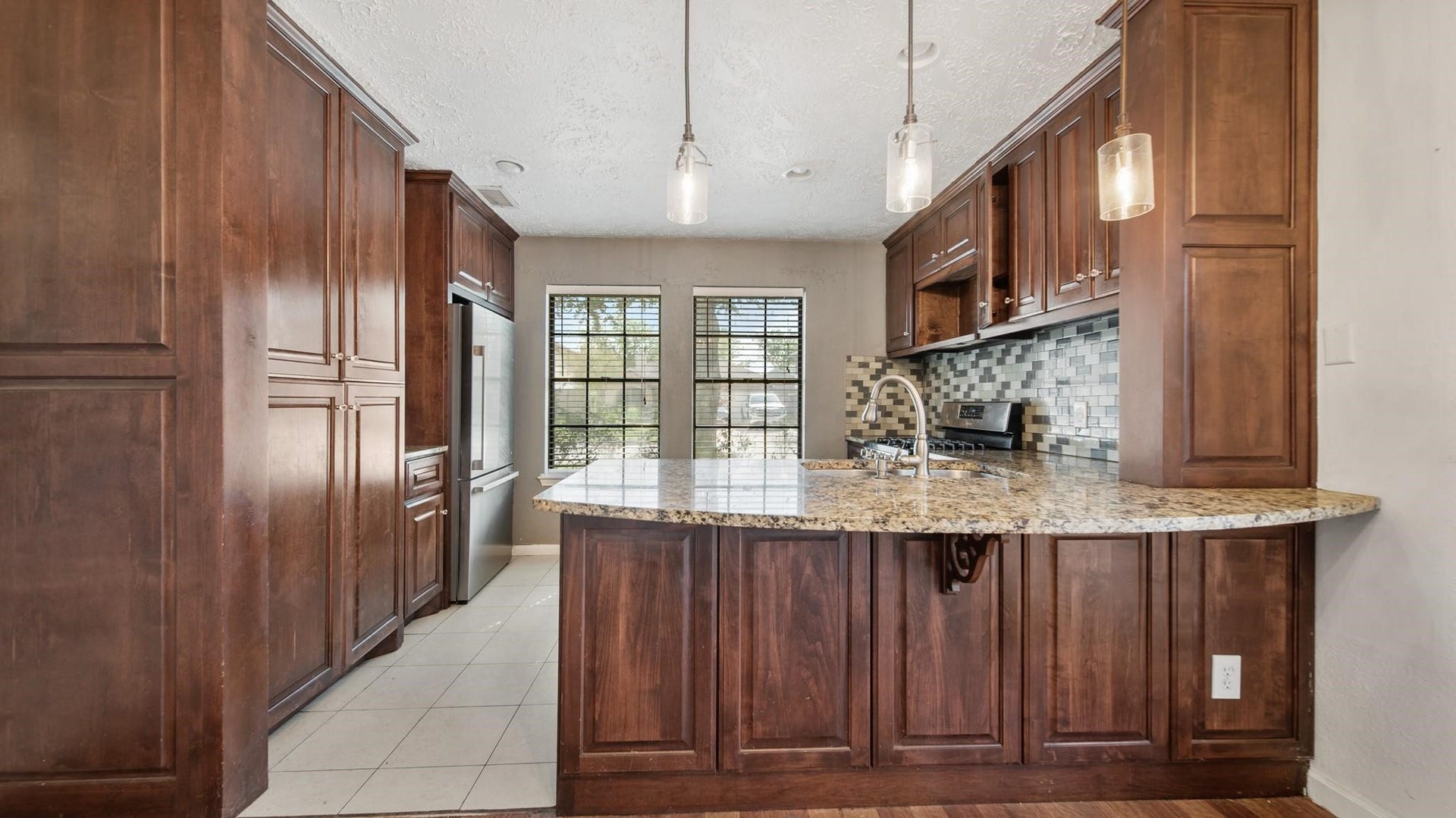 2012 Sandy Knoll Drive, Missouri City, TX 77489 Kitchen featuring rich wood cabinetry, granite countertops, breakfast bar, and stainless steel appliances.