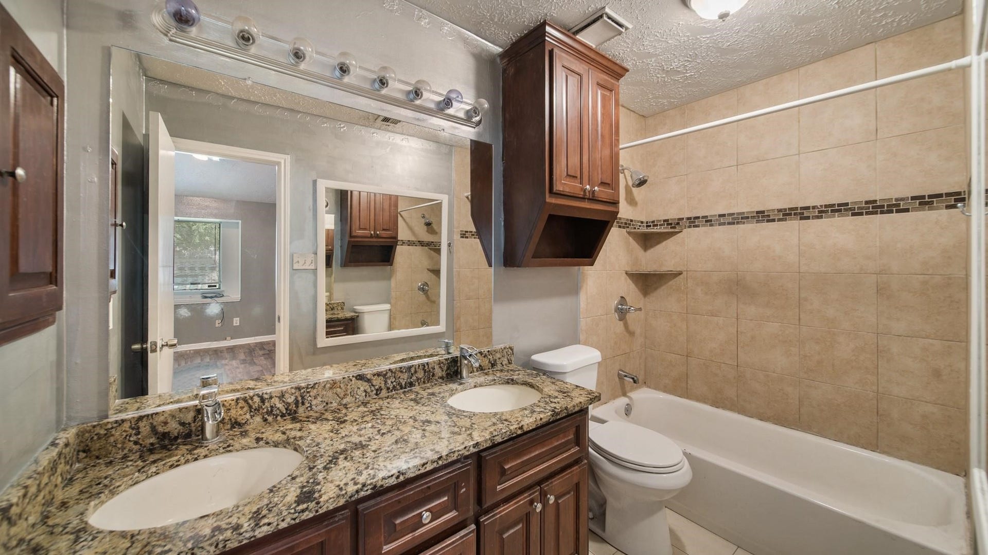 2012 Sandy Knoll Drive, Missouri City, TX 77489 Primary ensuite bathroom featuring a dual-sink granite vanity, wood cabinetry, and tub/shower combination.