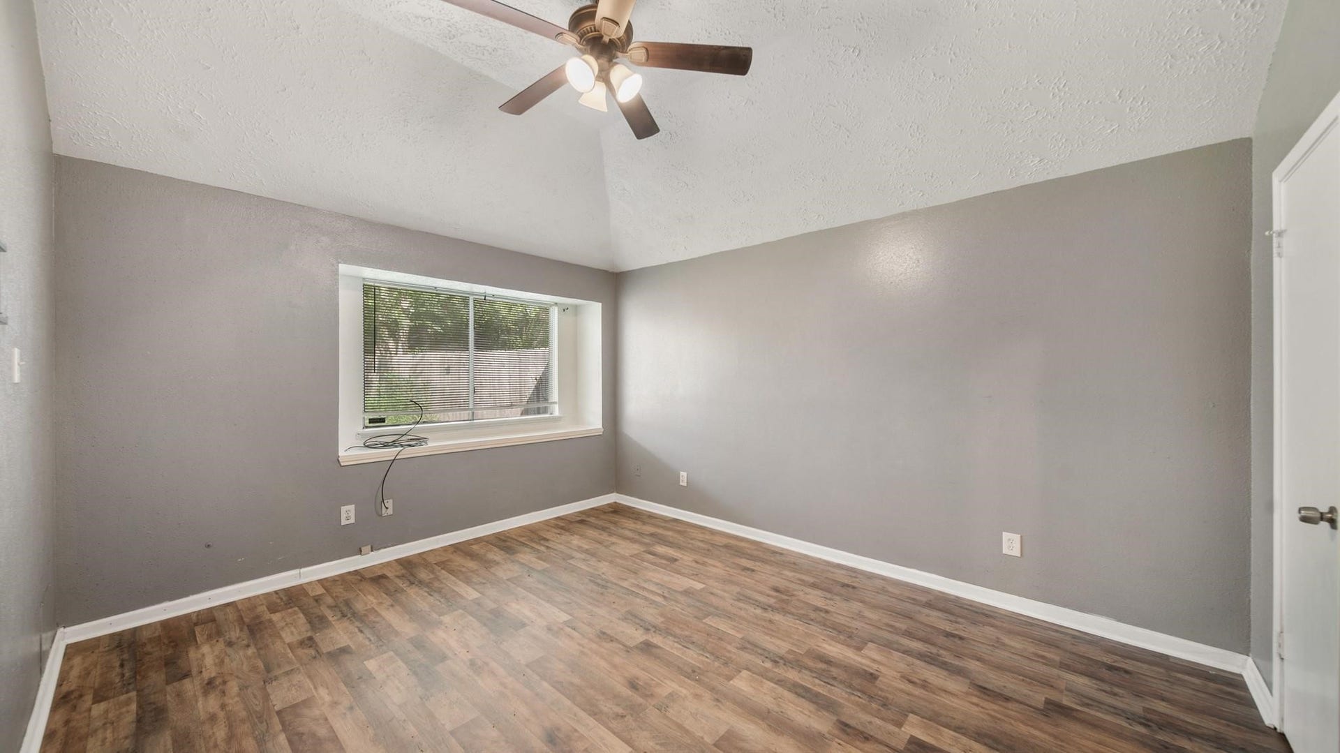 2012 Sandy Knoll Drive, Missouri City, TX 77489 Primary bedroom featuring a vaulted ceiling, wood-look flooring, and natural light.