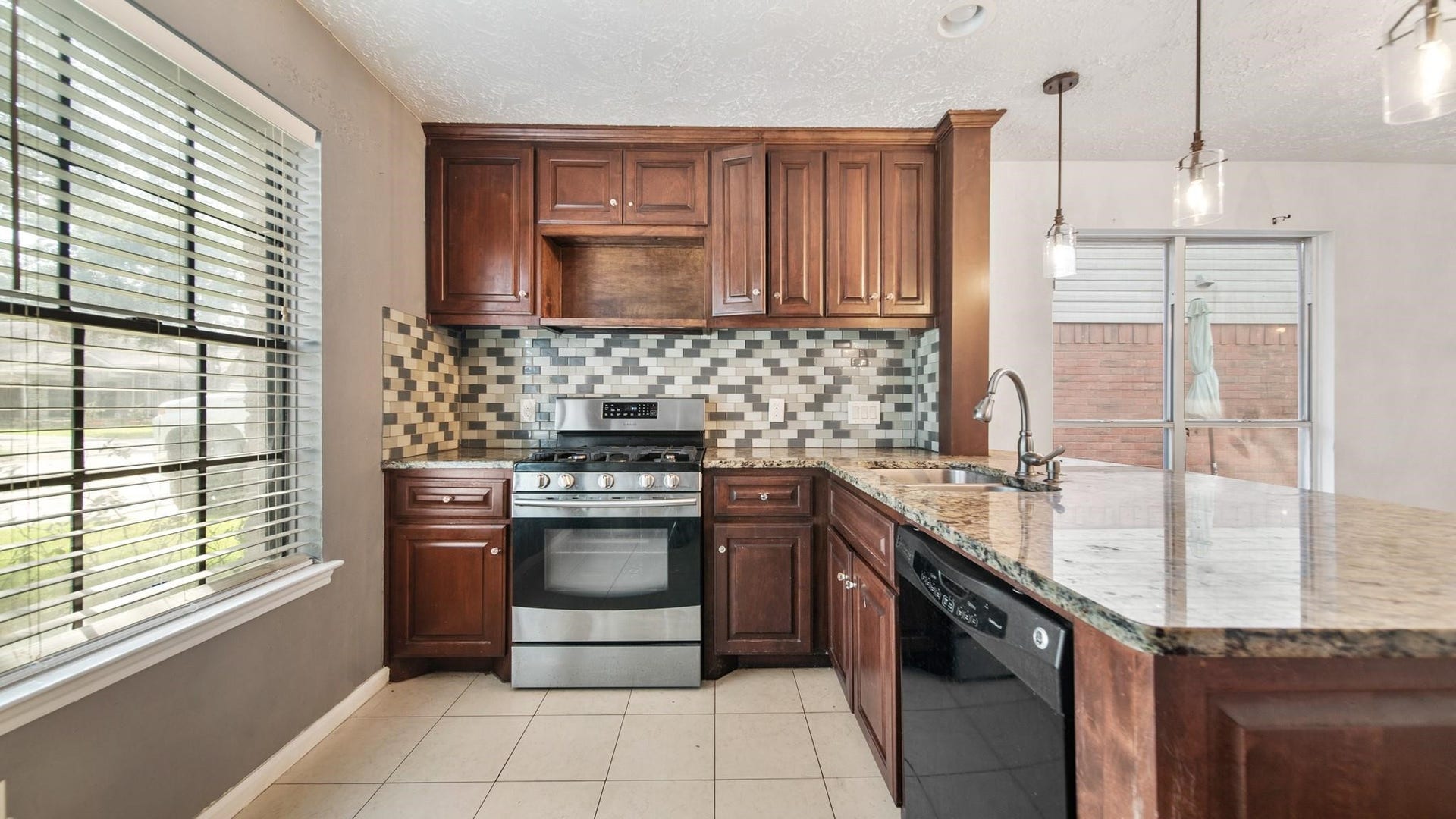 2012 Sandy Knoll Drive, Missouri City, TX 77489 Additional view of the kitchen showcasing granite countertops, tile backsplash, stainless steel gas range, and ample cabinet space.
