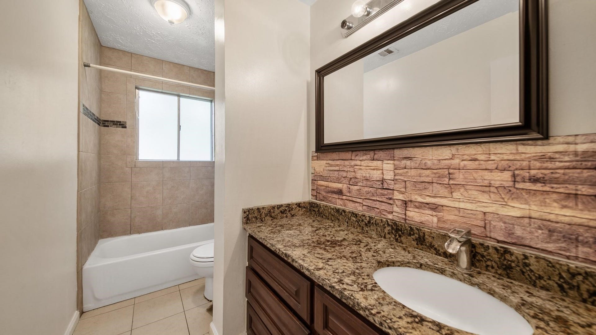2012 Sandy Knoll Drive, Missouri City, TX 77489 Shared bathroom featuring a granite vanity and tub/shower combination with tile surround.