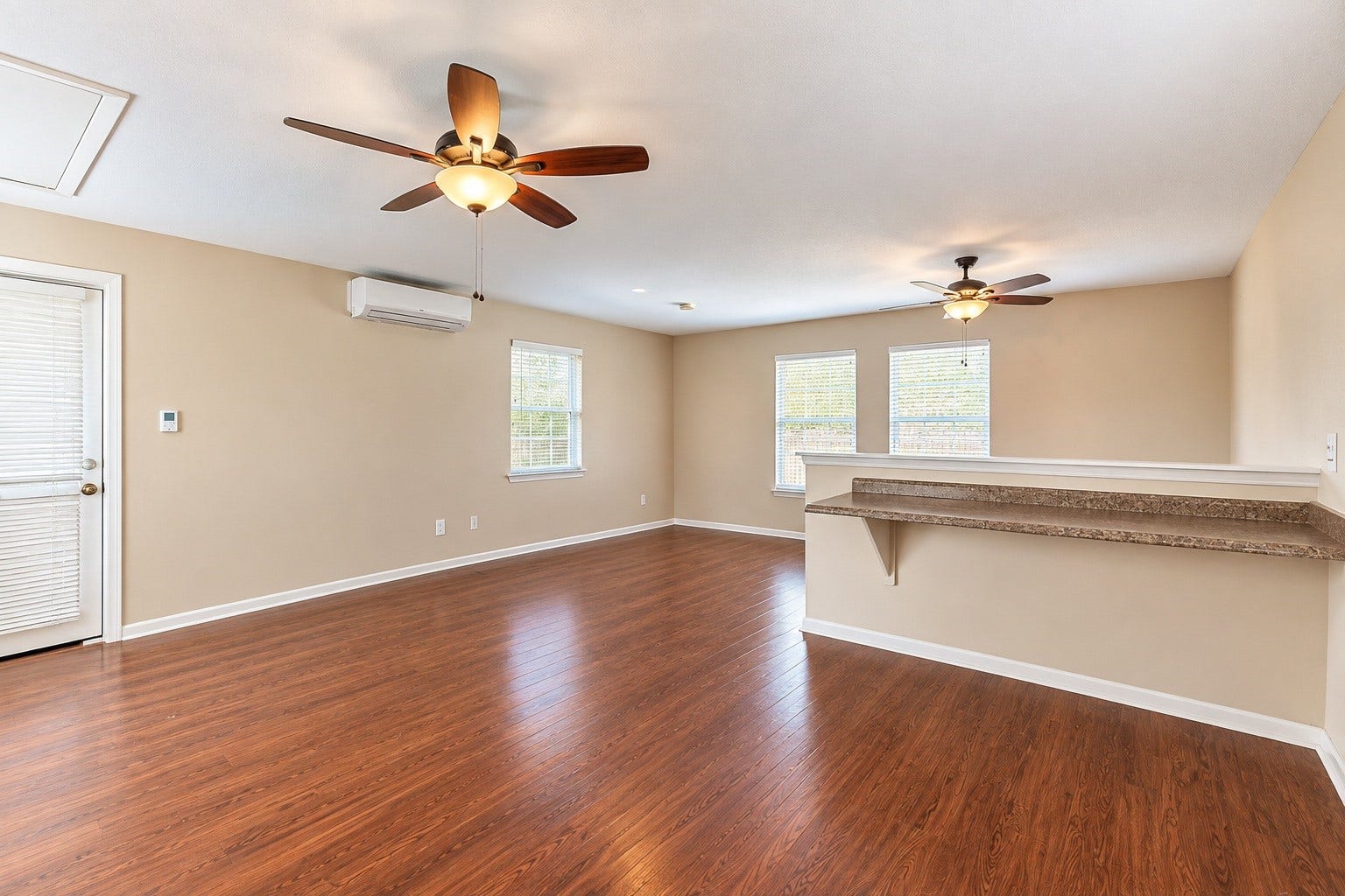 4030 Larkspur Street, Alvin, TX 77511 Spacious detached living area with warm wood-look flooring, ceiling fans, and ample natural light from multiple windows, offering a comfortable and inviting atmosphere.