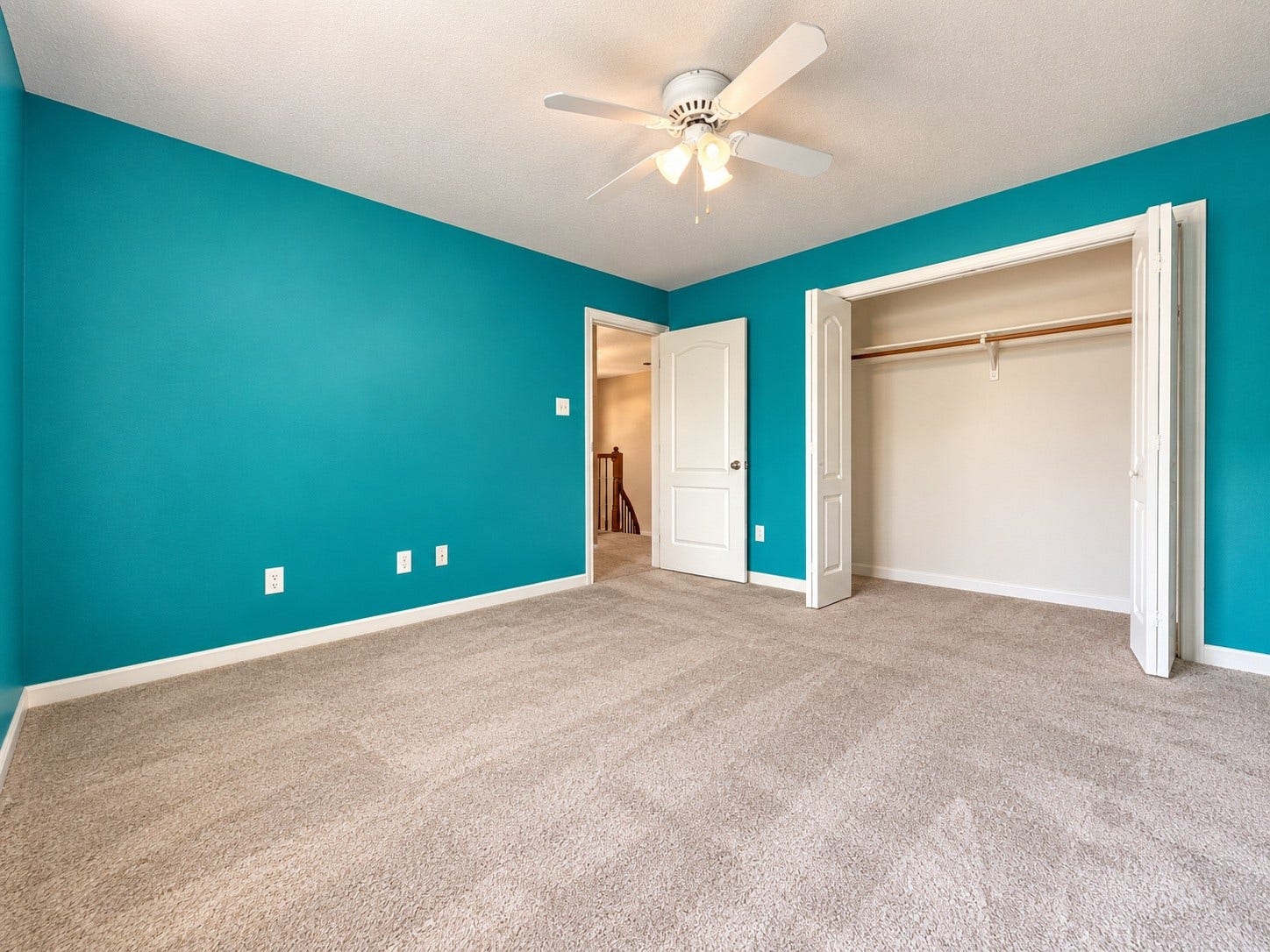 4030 Larkspur Street, Alvin, TX 77511 Spacious bedroom featuring vibrant teal walls, plush carpeting, a ceiling fan, and a convenient, large closet with double doors.