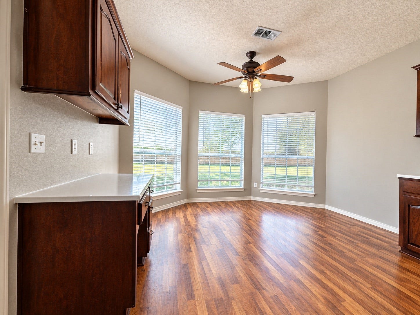 4030 Larkspur Street, Alvin, TX 77511 Bright breakfast area with large windows, wood-look floors, and a ceiling fan, offering an inviting space for meals and gatherings.