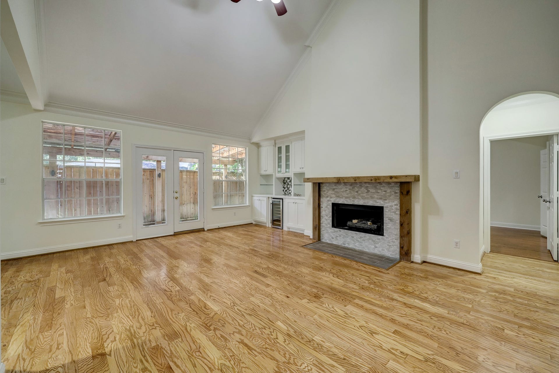 3608 Timberside Circle Drive, Houston, TX 77025 FAMILY ROOM (Unstaged): Bright and spacious with vaulted ceilings, hardwood floors, and a cozy fireplace with built-in cabinetry. Large windows and French doors bring in natural light and offer access to the backyard.