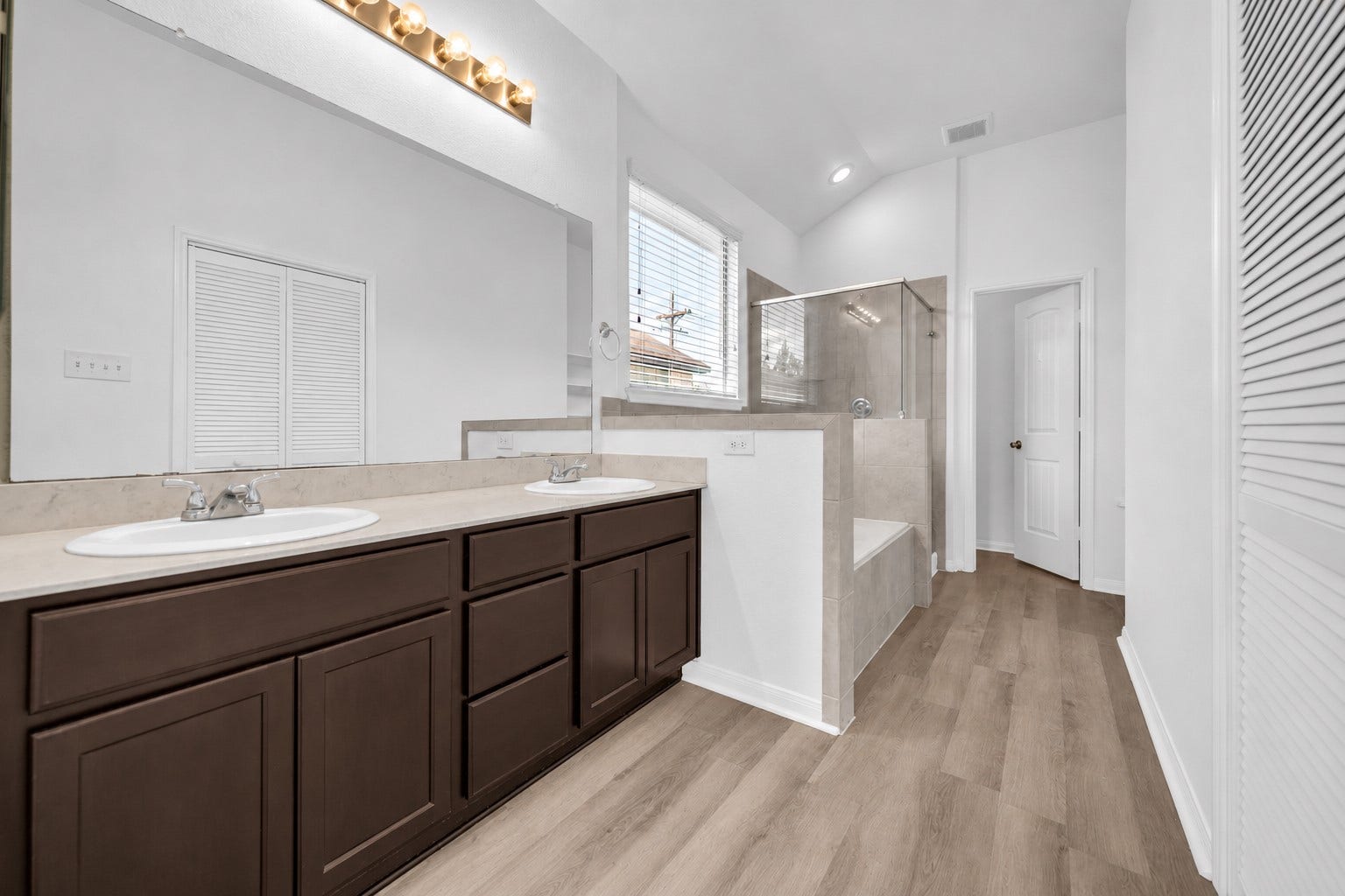 4707 Waukegan Road, Conroe, TX 77306 Primary bathroom features a dual-sink vanity with ample cabinet storage, along with a separate shower and soaking tub for a relaxing retreat.