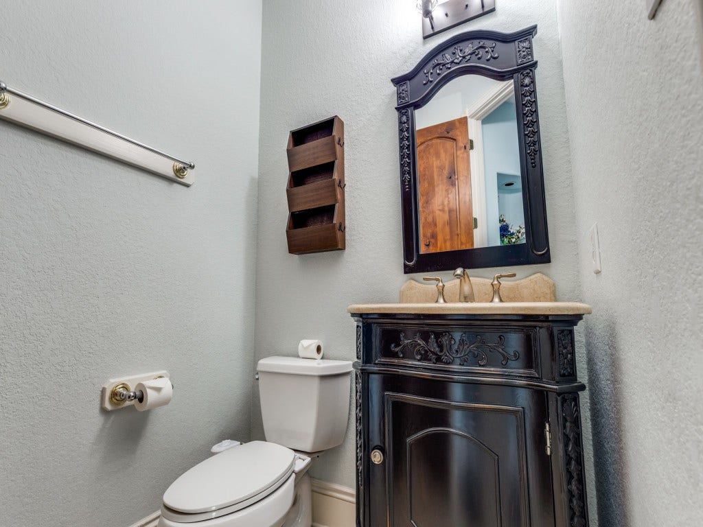 2811 Princeton Street, Houston, TX 77009 This is a 1/2 bathroom featuring a decorative vanity with a dark wood finish and intricate detailing. The light gray walls create a clean, fresh look.