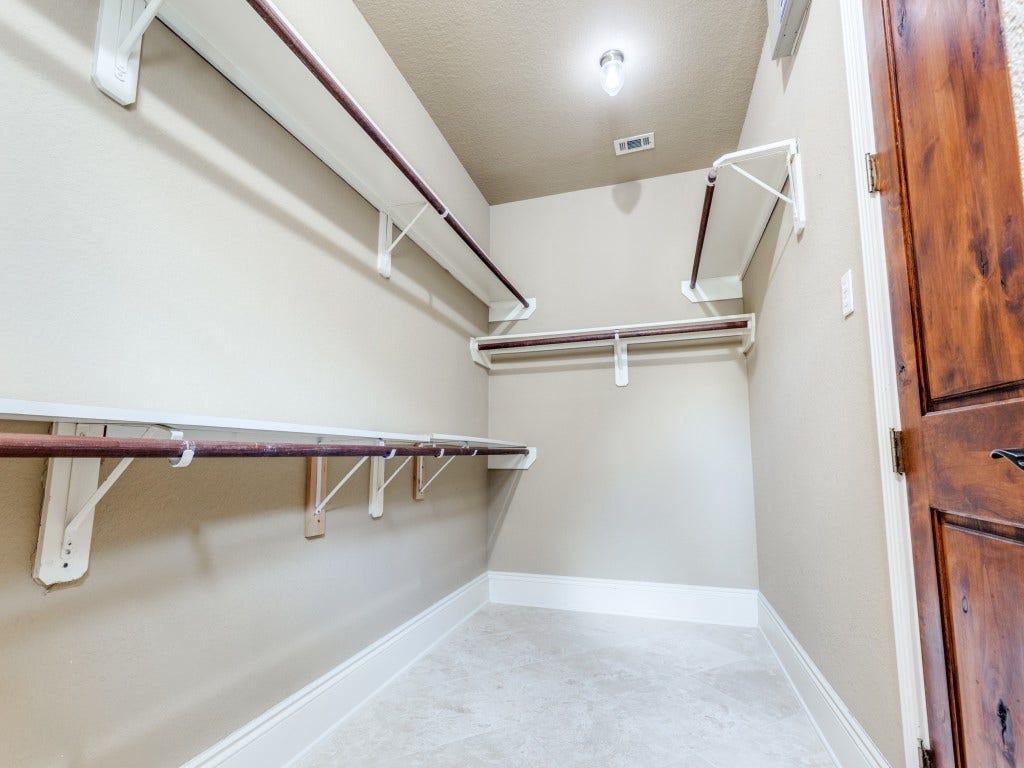 2811 Princeton Street, Houston, TX 77009 Primary walk-in closet is spacious with ample shelving and hanging space, featuring neutral walls, a light fixture, and a hard wood door.